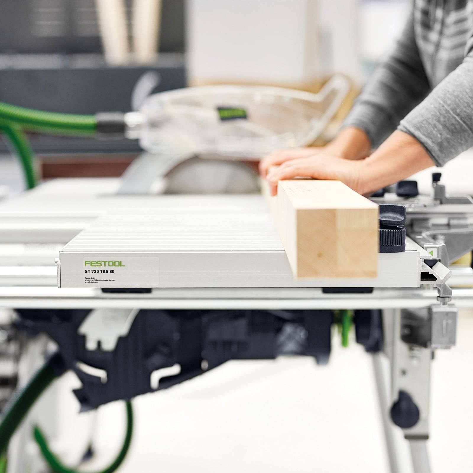 Eine Person, die eine Festool-Säge verwendet, um einen Holzbalken in einer Werkstatt zu schneiden, demonstriert präzises Holzbearbeiten.