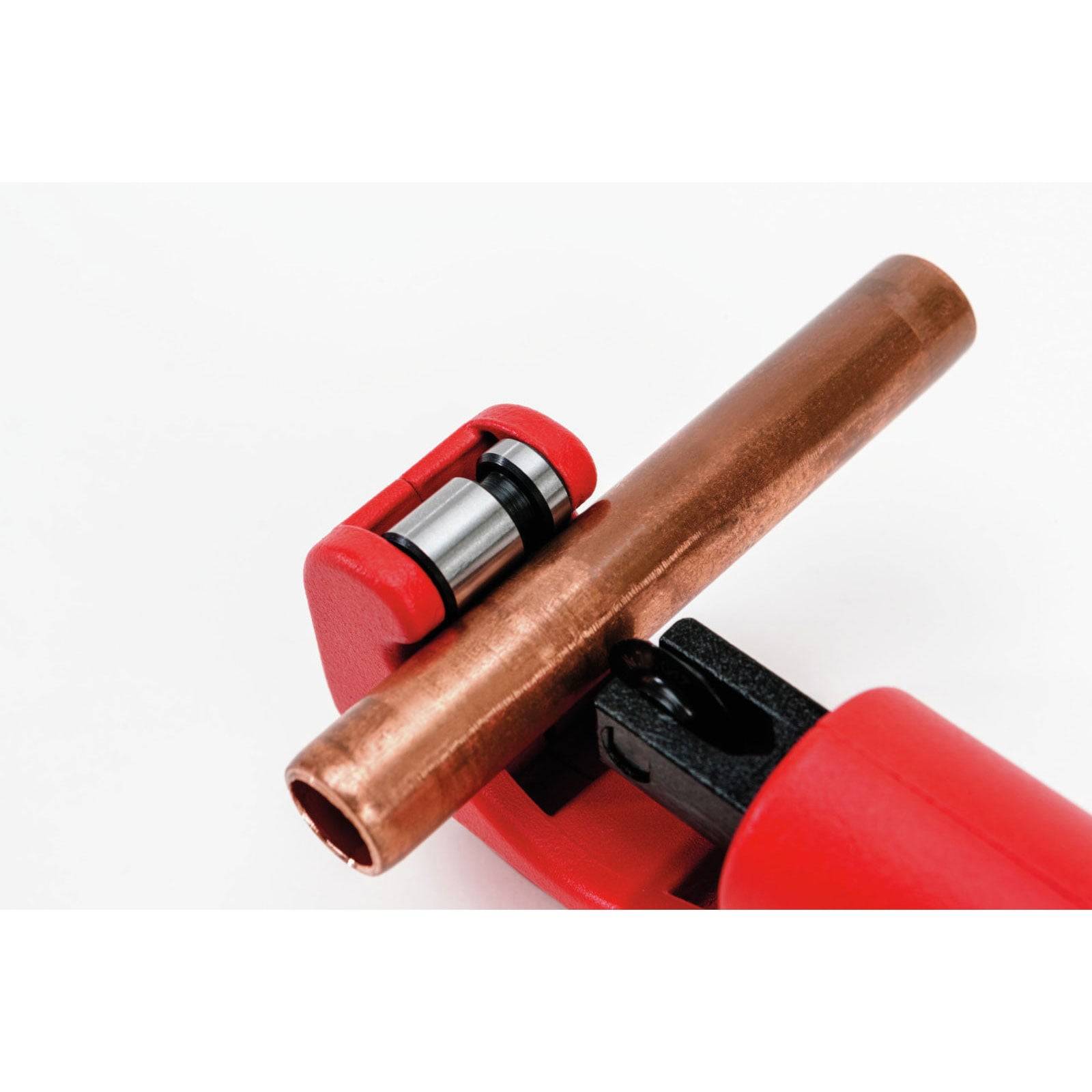 Eine Nahaufnahme eines roten Rohrabschneiders, der ein Kupferrohr umklammert und seine effiziente Nutzung beim Schneiden oder Trimmen von Rohren demonstriert.