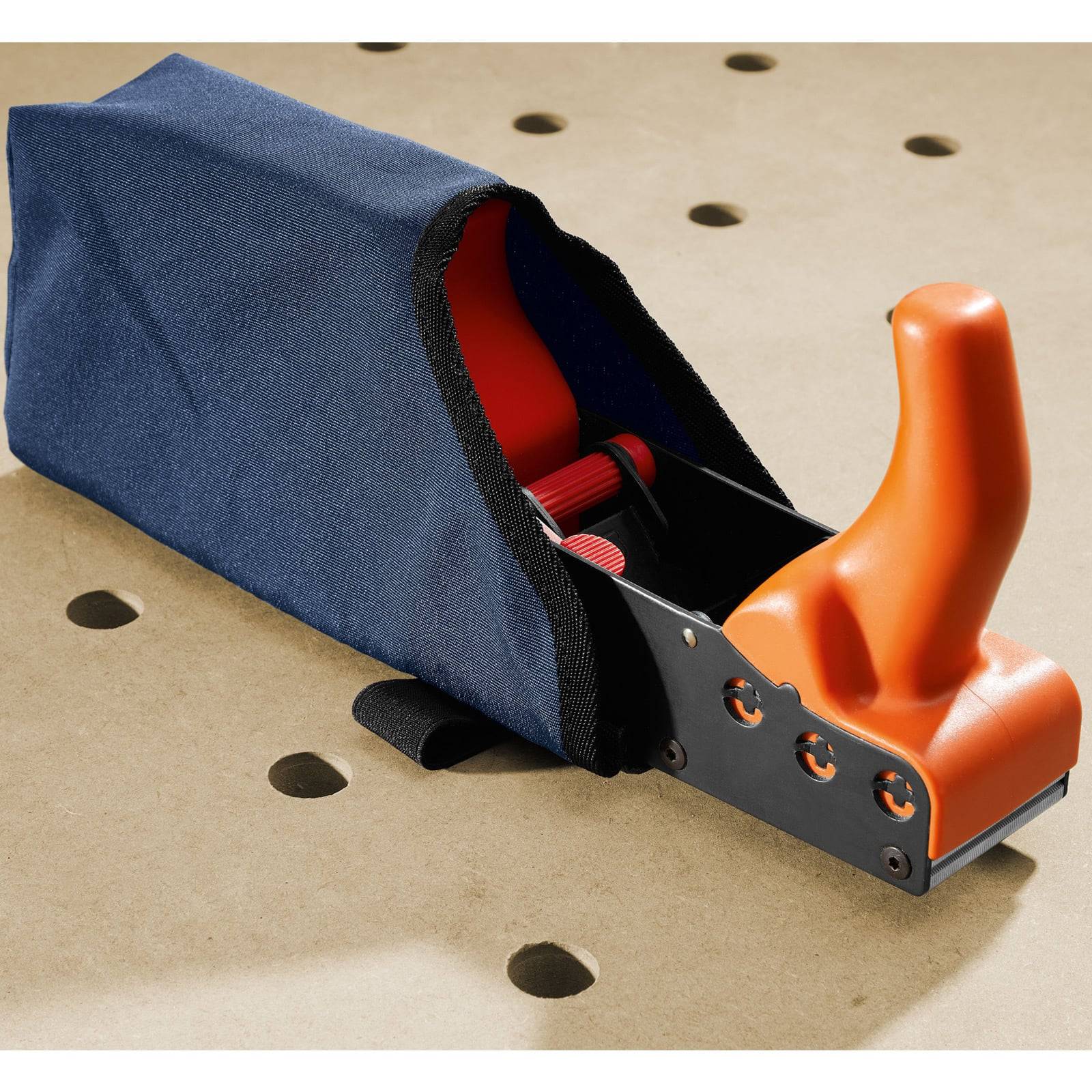 Ein manueller Handhobel mit orangefarbenem Griff und blauem Staubsack, ruhend auf einer perforierten Werkbankoberfläche.