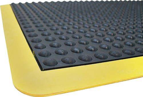 Schwarze Gummimatte mit rutschfester Oberfläche und erhabenen kreisförmigen Noppen auf einem gelben abgeschrägten Rand, entwickelt zur Verbesserung der Bodensicherheit und Rutschverhinderung.