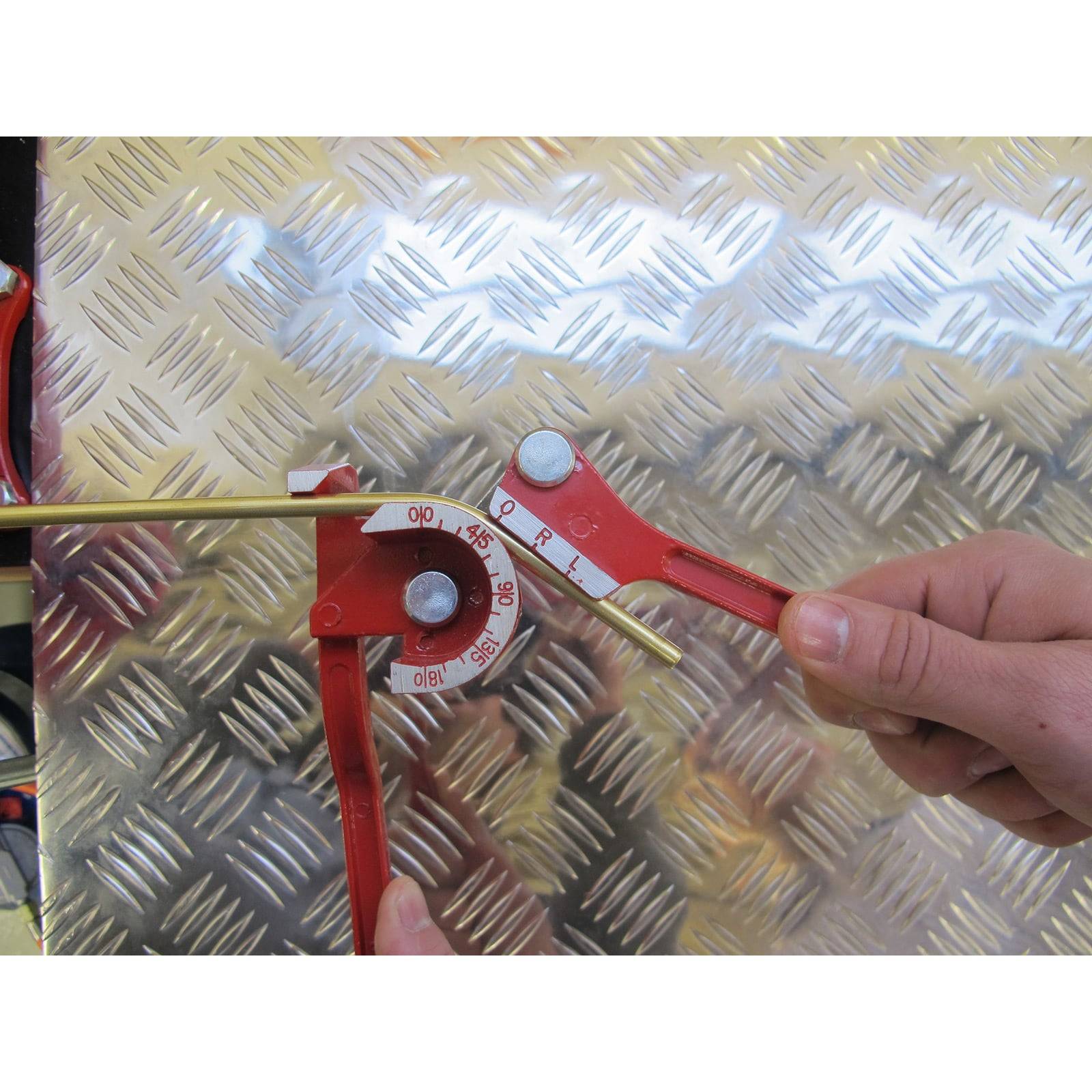 Ein manuell betriebenes Biegwerkzeug biegt eine Metallstange gegen eine strukturierte Metalloberfläche und demonstriert, wie Materialien präzise geformt werden können.