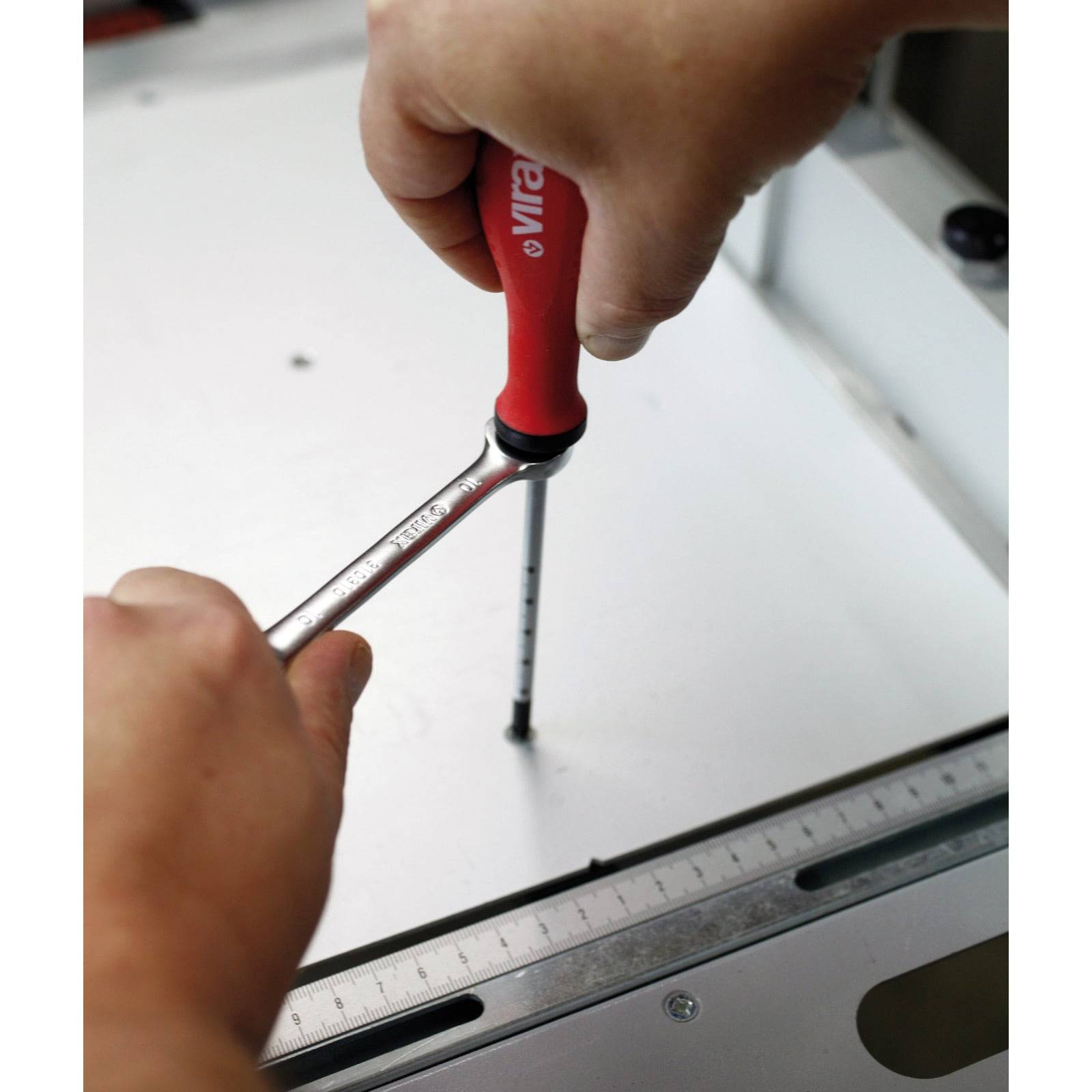 „Person, die einen Schraubendreher mit rotem Griff verwendet, um eine Schraube auf einer flachen Oberfläche zu befestigen.