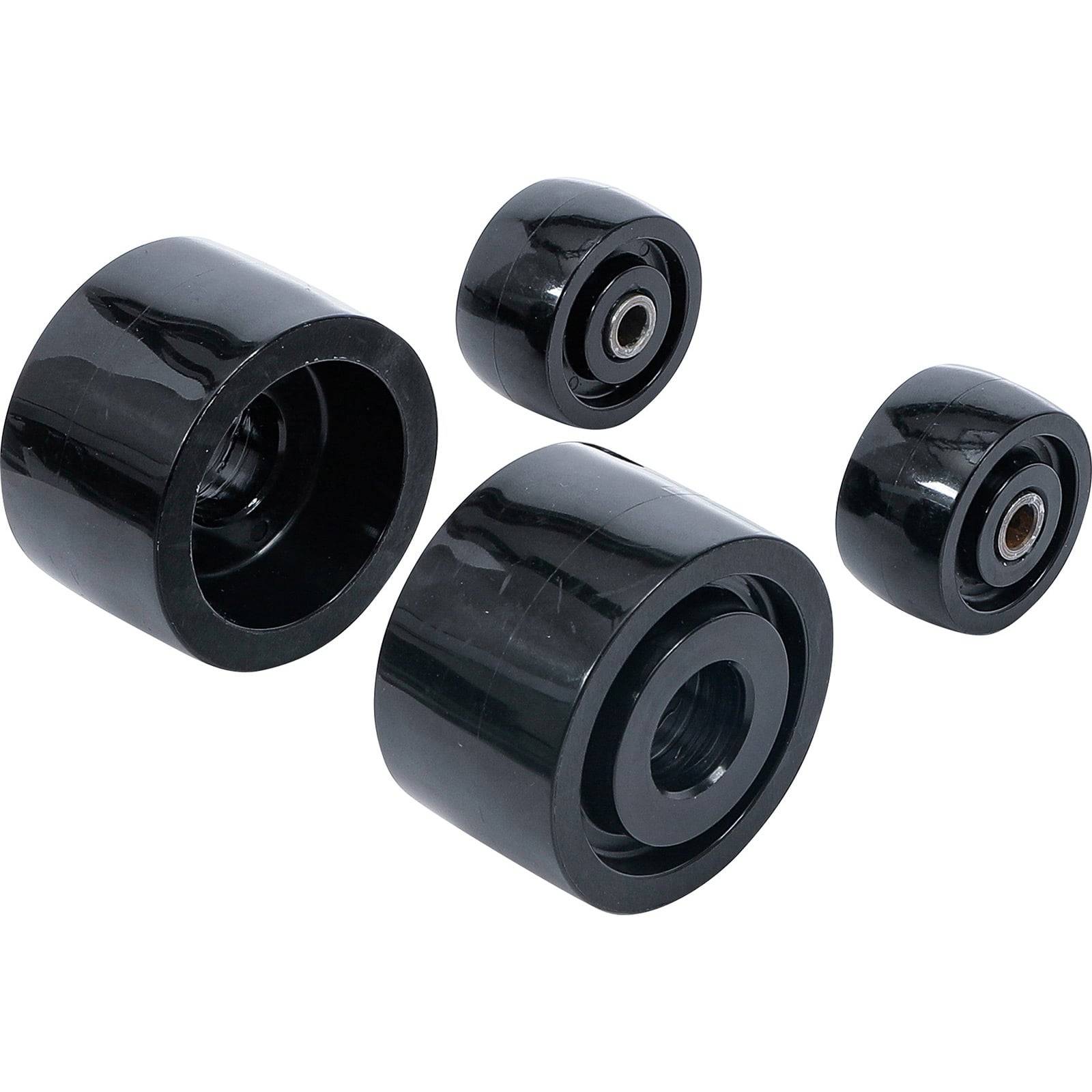 Vier schwarze Skateboard-Räder, zwei größere und zwei kleinere, sind in einer Gruppe angeordnet. Die Räder haben sichtbare Kugellager in ihrem Inneren.