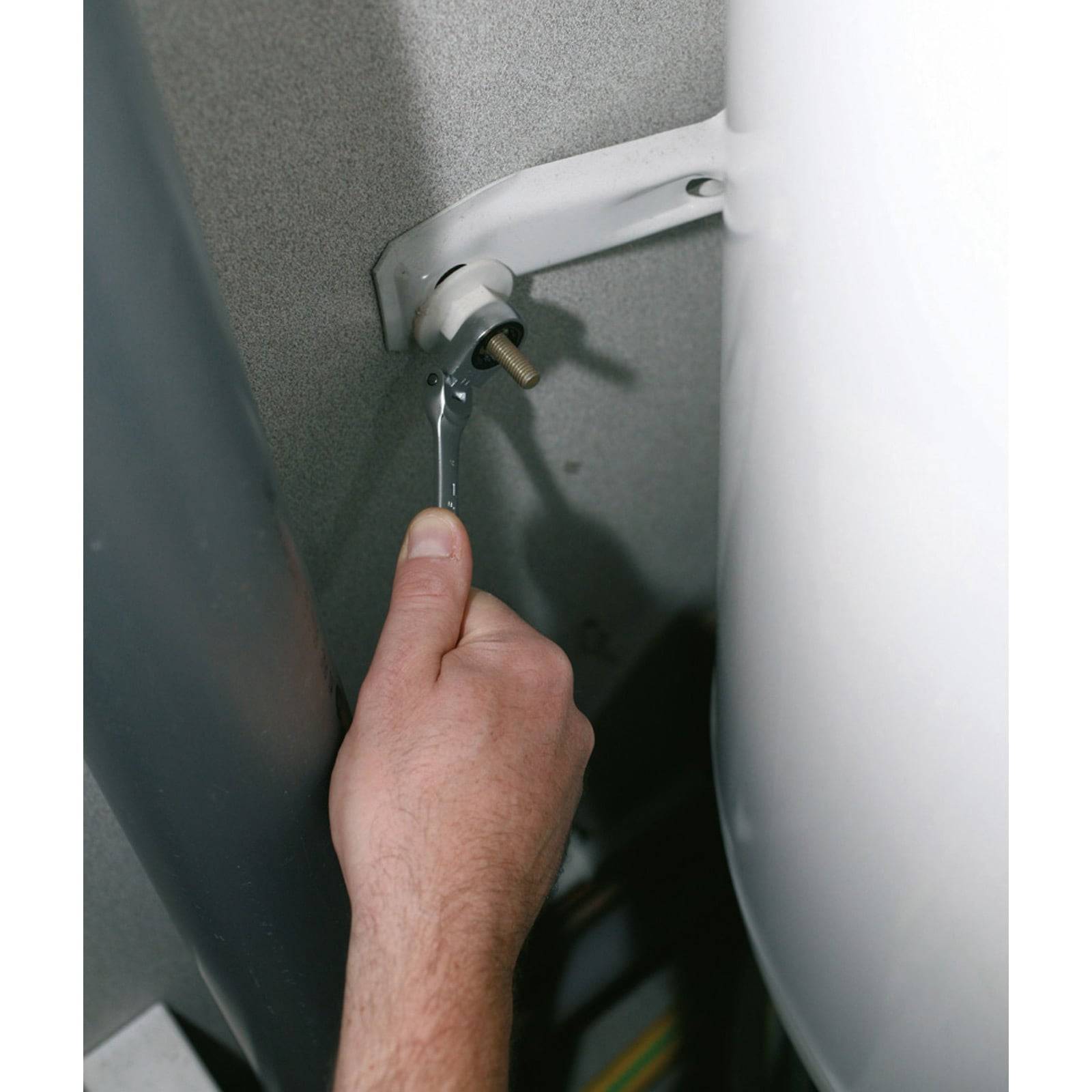 Eine Person benutzt einen Schraubenschlüssel, um eine Schraube an einer Wandhalterung festzuziehen und führt damit eine Wartungs- oder Reparaturaufgabe durch.