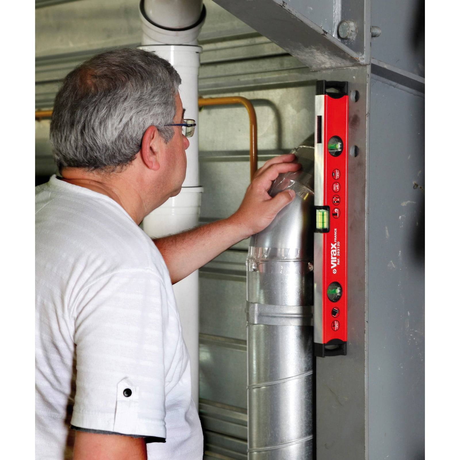 Eine Person verwendet eine rote Wasserwaage, um Metallrohre auszurichten und sicherzustellen, dass sie senkrecht gerade sind. Sie ist konzentriert und justiert das Rohr entsprechend.