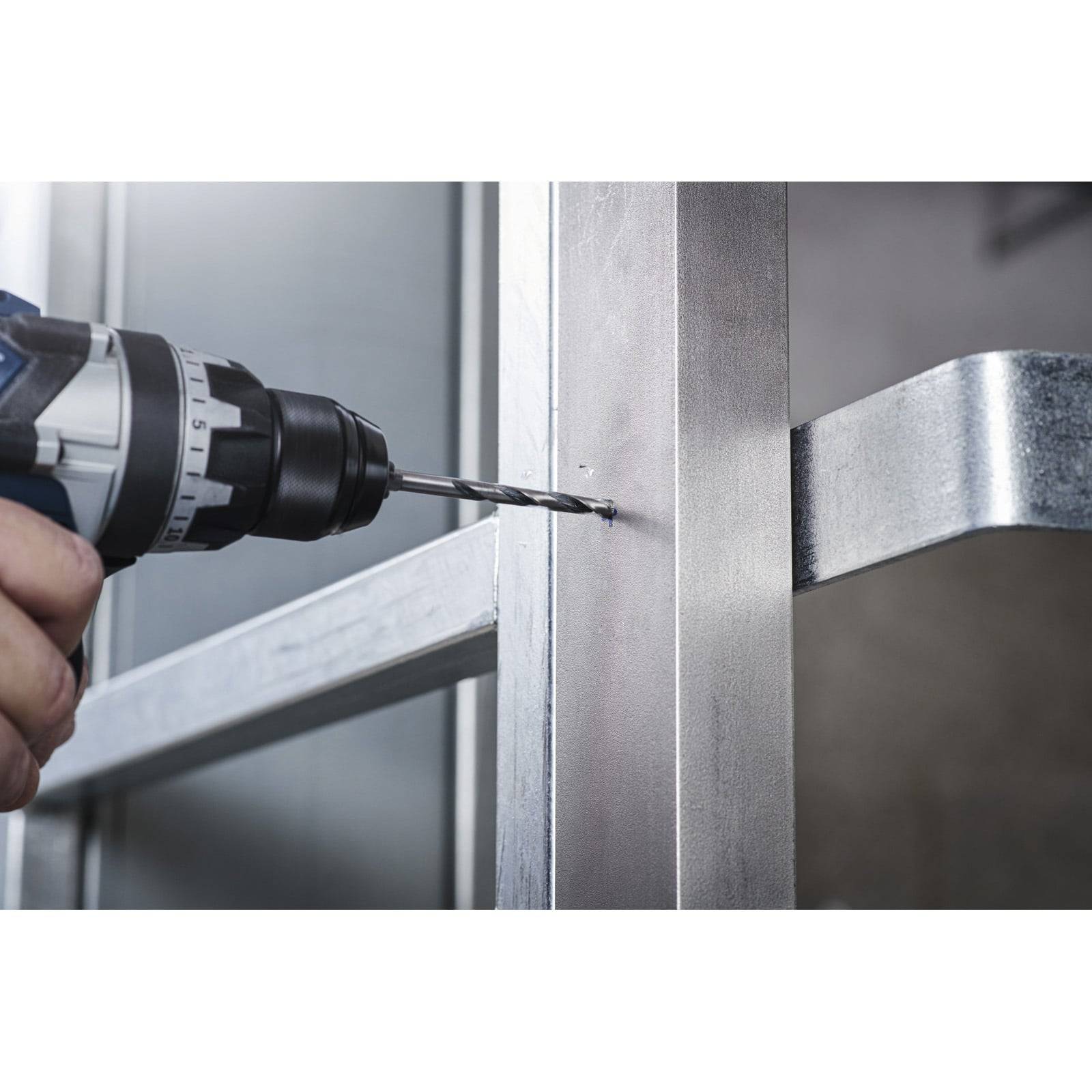 Eine Nahaufnahme einer Person, die einen Elektrobohrer verwendet, um ein Loch in eine Metalloberfläche zu bohren, höchstwahrscheinlich für Installations- oder Reparaturarbeiten.