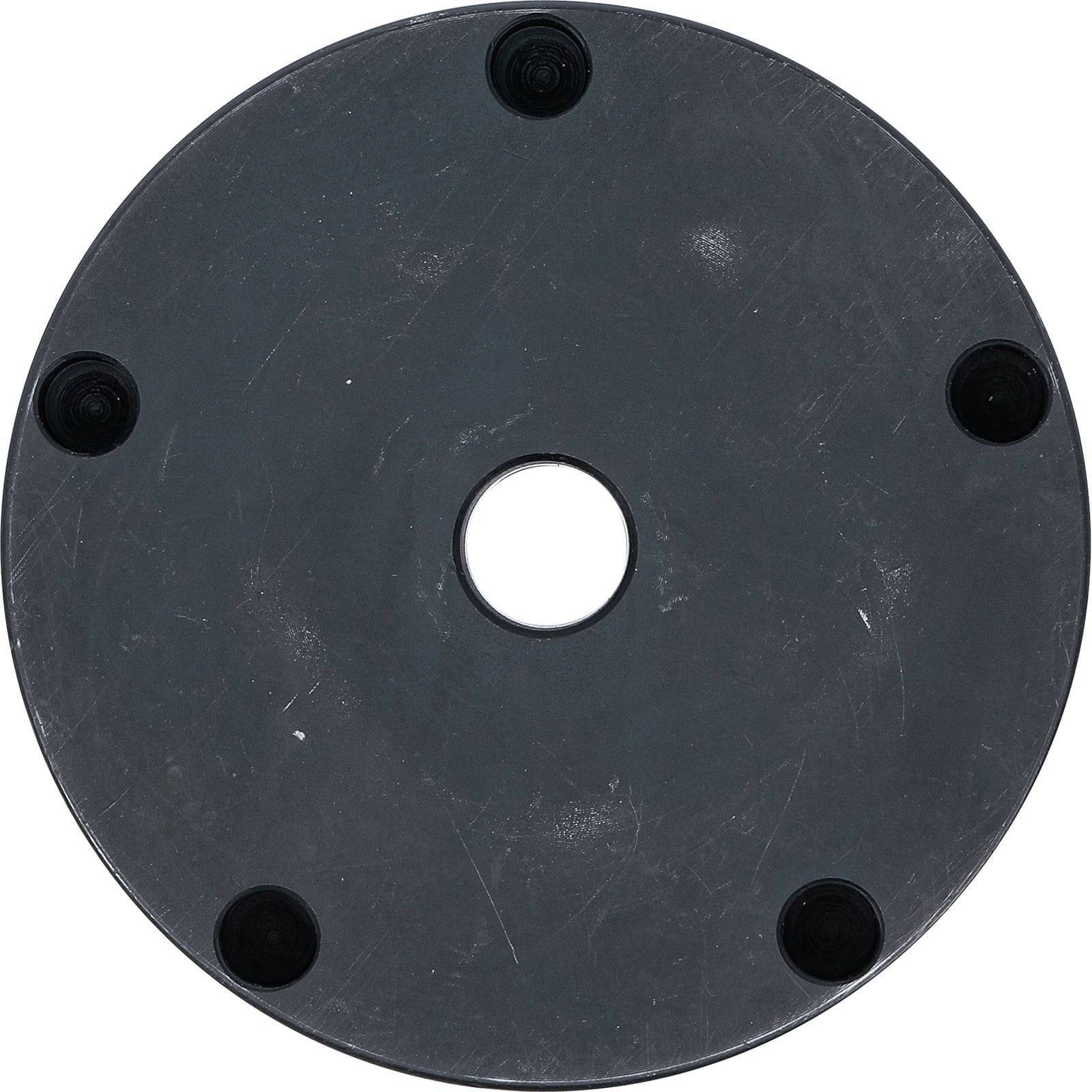 Eine runde, schwarze scheibenförmige Fläche mit einem zentralen Loch und fünf kleinen, gleichmäßig am Rand verteilten Kreisen.