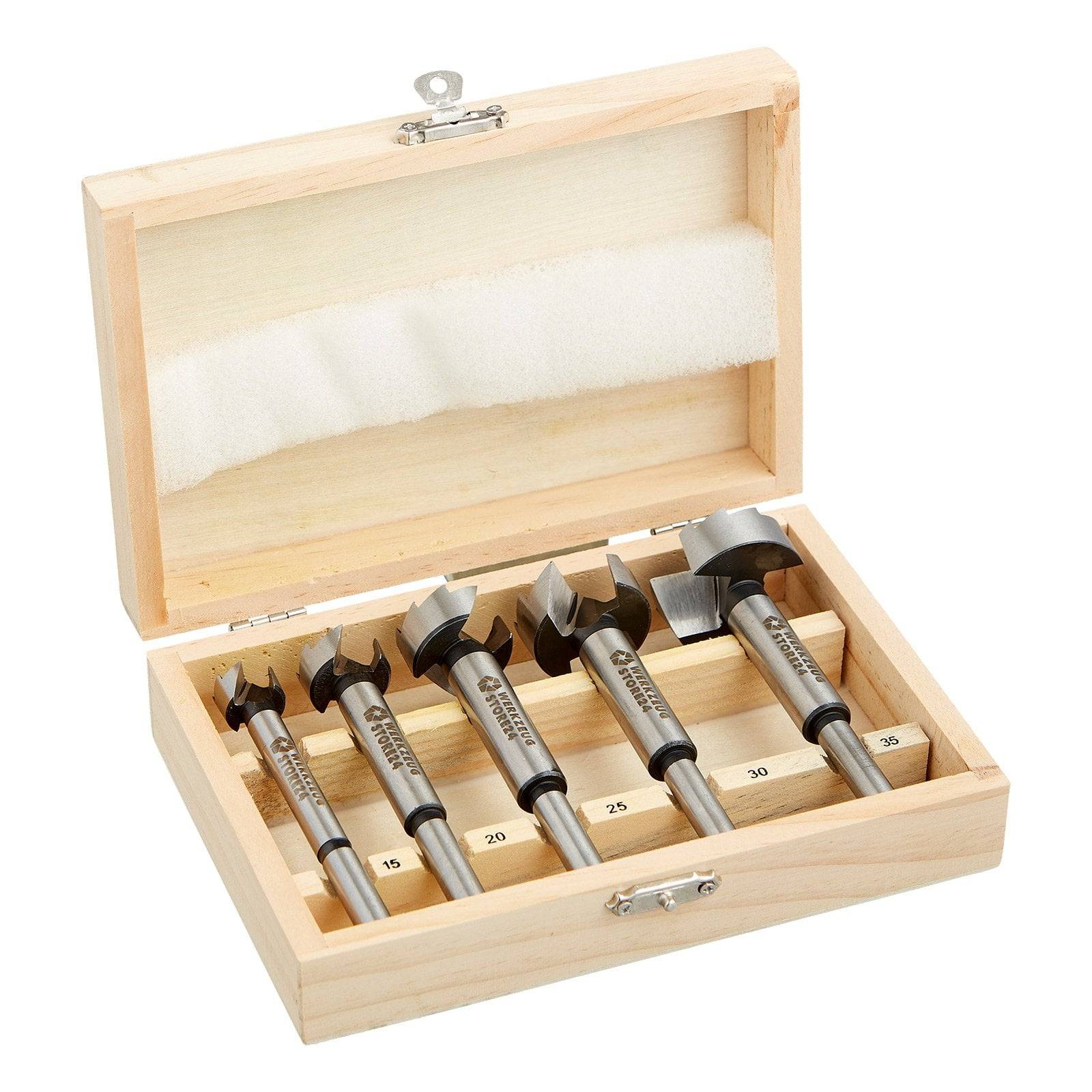 Eine Holzbox, die fünf Metallbohrer in unterschiedlichen Größen zeigt, von 15 bis 35 beschriftet, die sauber in einzelnen Fächern angeordnet sind.