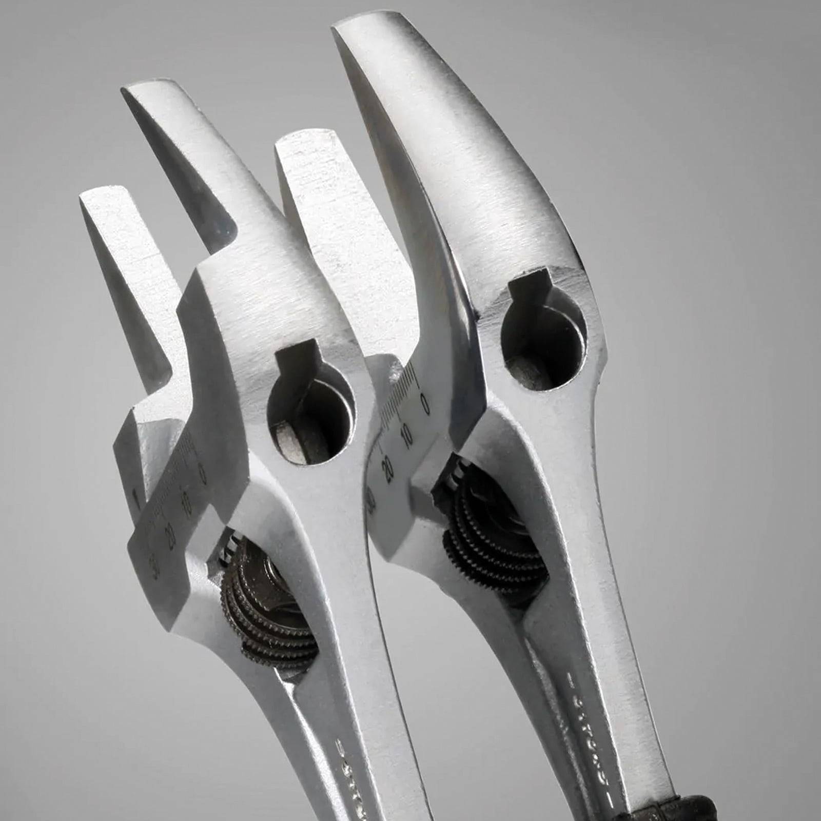 Zwei verstellbare Schraubenschlüssel aus Metall, die mit offenen Backen nach oben positioniert sind und ihre Mechanismen sowie polierten Oberflächen vor einem grauen Hintergrund präsentieren.