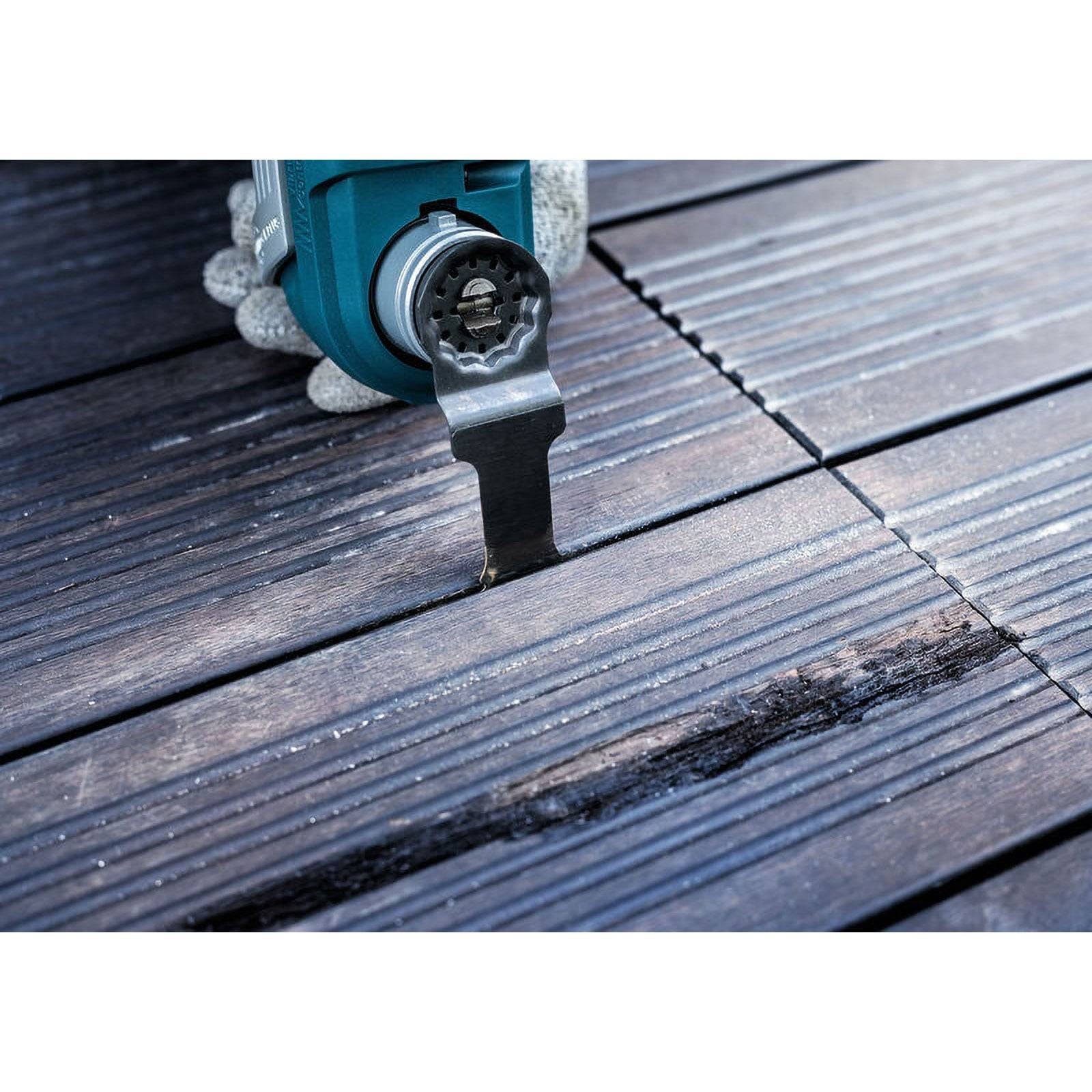 Eine Elektrowerkzeug mit einer Sägeblatt trimmt eine dunkle Holzterrasse und korrigiert beschädigte Rillen auf der Oberfläche.