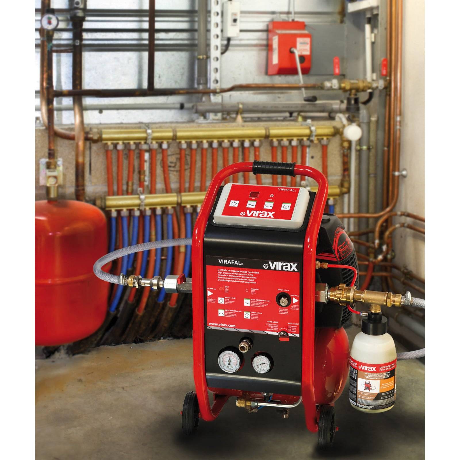 Industrielle Ausrüstung der Marke 'Virax' zur Wasserdruckprüfung in einem Versorgungsraum. Rohre, Manometer und angeschlossene Schläuche sind sichtbar.