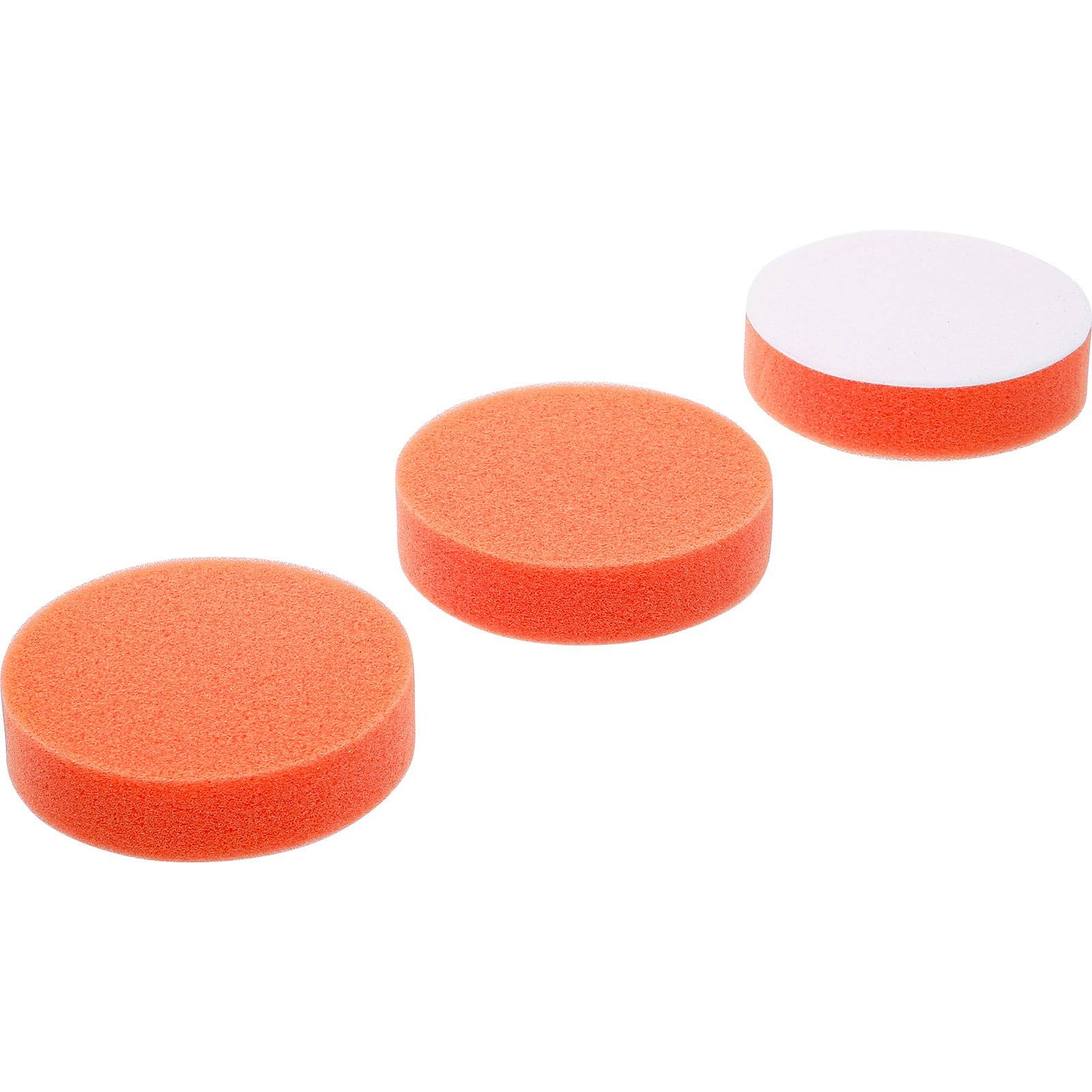 Drei orangefarbene Schaumstoffpads in einer Reihe, wobei der letzte eine weiße Rückseite zeigt.