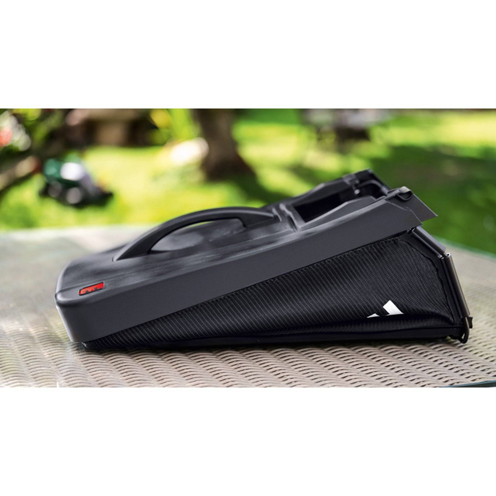 Tragbarer, rechteckiger Akkupack in einer Grasum­gebung, mit sichtbarem Logo und strukturierter Seitenfläche.