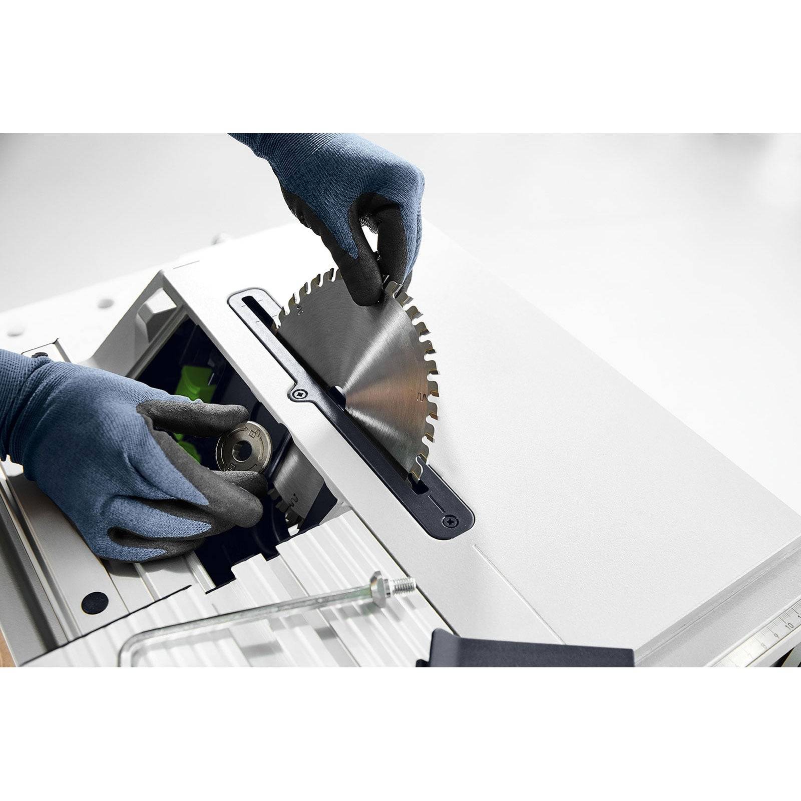 Eine Person mit Schutzhandschuhen justiert eine Kreissägeblatt auf einer Tischkreissäge und unterstreicht dabei Sicherheitspraktiken bei der Werkzeugwartung.