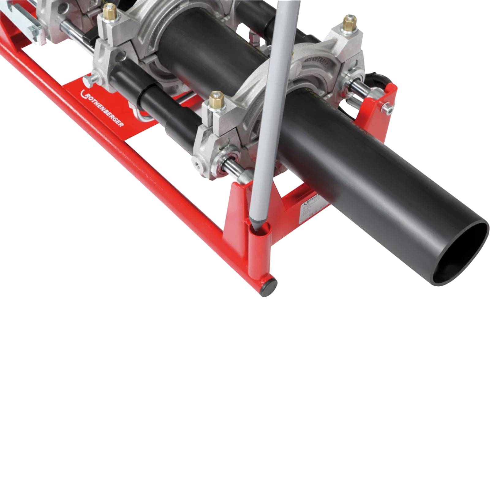 Ein schwarzes Rohr, das von einer roten mechanischen Verschweißungsmaschine gehalten wird, die zum Verbinden zweier Rohrsegmente verwendet wird.