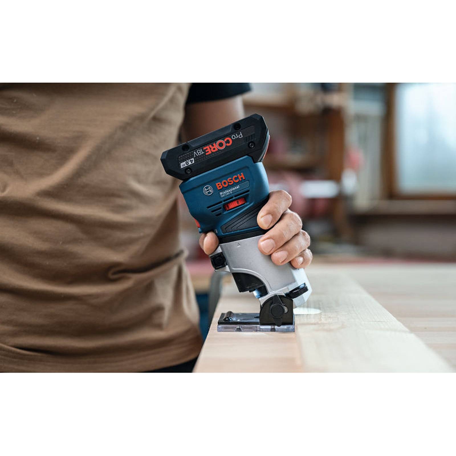 Eine Person verwendet einen Bosch-Router auf einer Holzoberfläche und demonstriert präzise Holzbearbeitung in einer Werkstattumgebung.