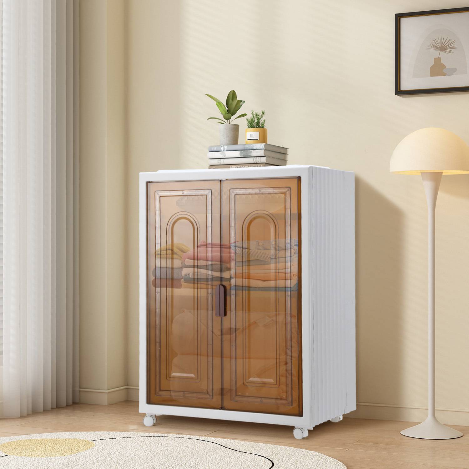Kompakte weiße Speicherschrank mit Glastüren in Bernsteinfarbe und Regalen, oben mit Büchern und kleinen Pflanzen in einem hellen Raum.