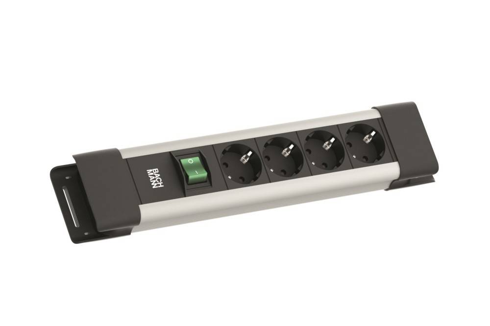 Eine Steckdosenleiste mit vier europäischen Steckdosen und einem grünen Ein/Aus-Schalter auf einer flachen rechteckigen Basis.