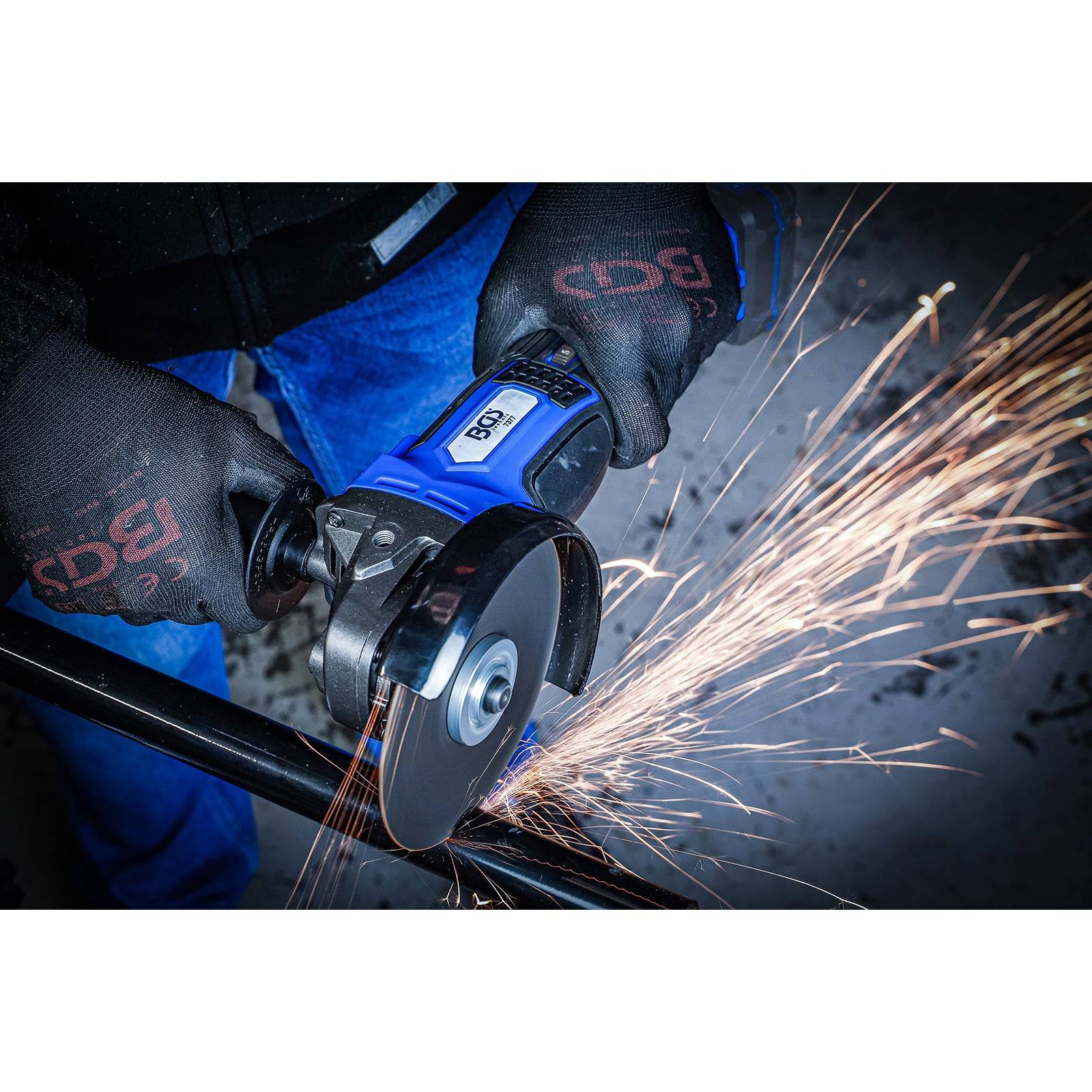 Eine Person mit Handschuhen verwendet einen Winkelschleifer und erzeugt dabei eine Funkengarbe beim Schneiden von Metall.