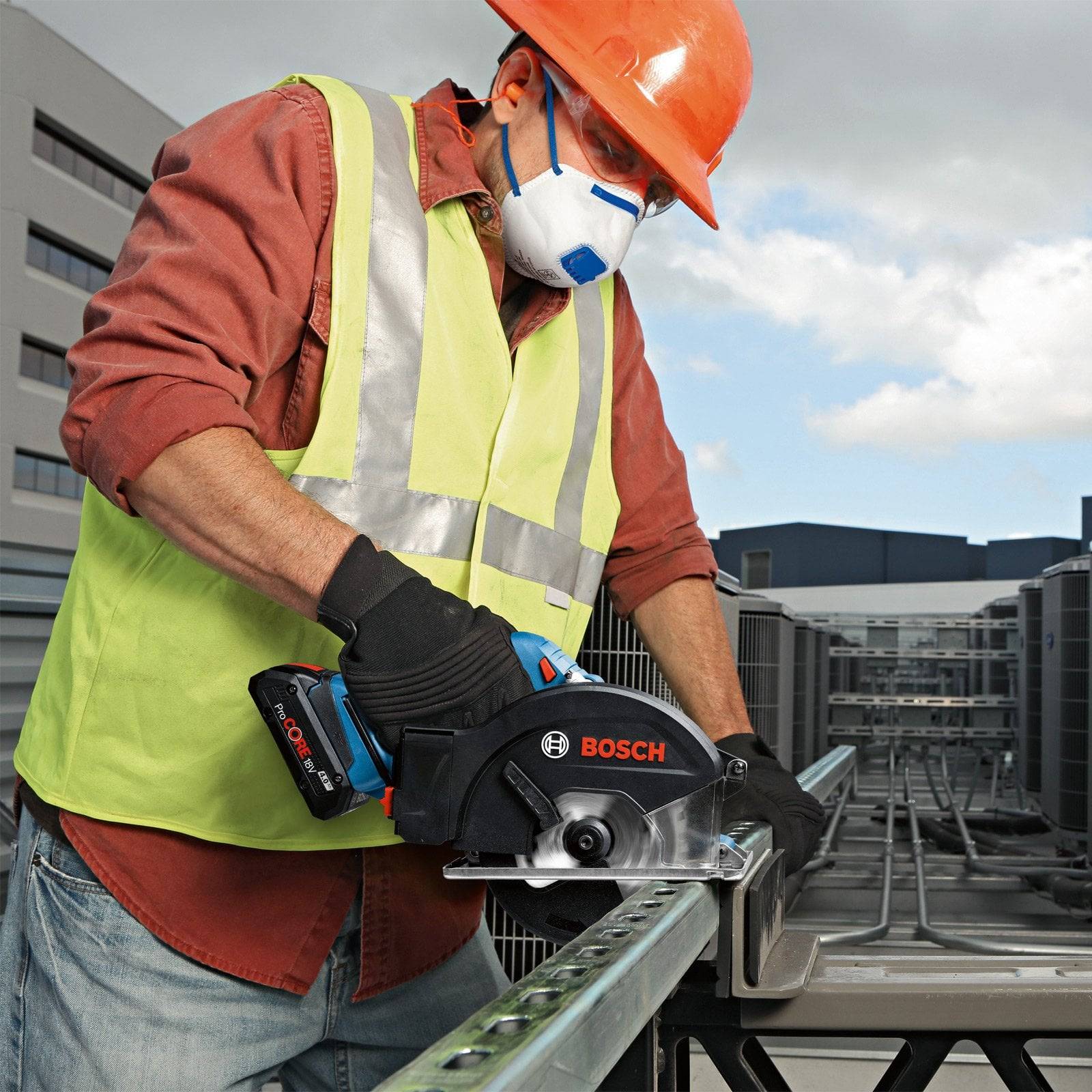 Ein Arbeiter in Sicherheitsausrüstung verwendet eine Bosch-Säge, um Metall auf einem Dach zu schneiden, umgeben von Gebäuden und Klimaanlagen.
