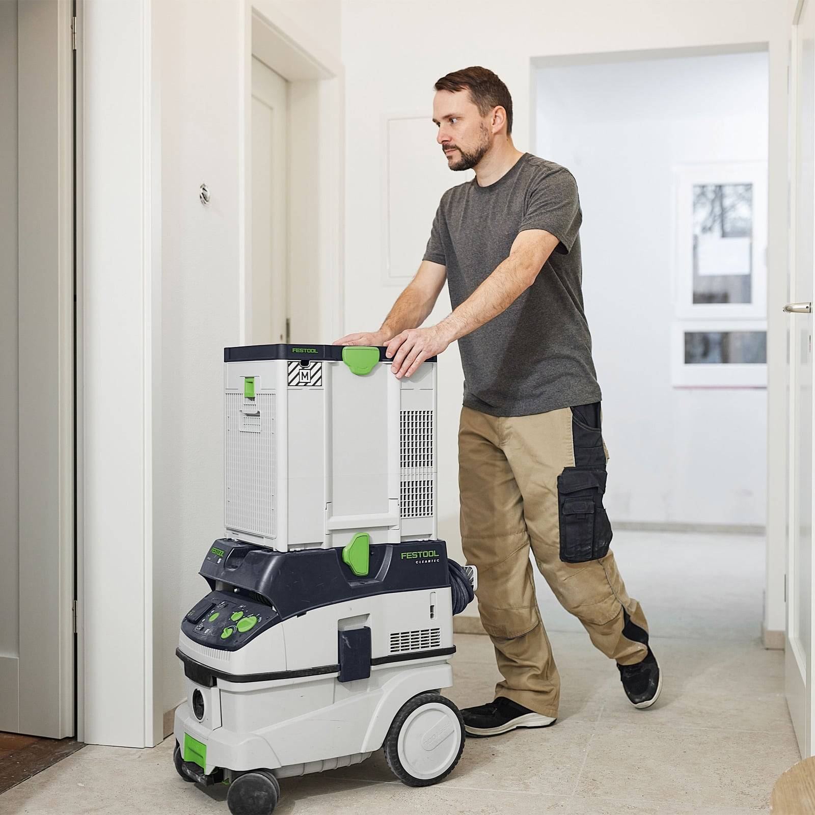 Eine Person bewegt eine mobile Werkzeugaufbewahrungseinheit mit Rollen in einem Flur, was auf Organisation und effiziente Werkzeugbeförderung hindeutet.