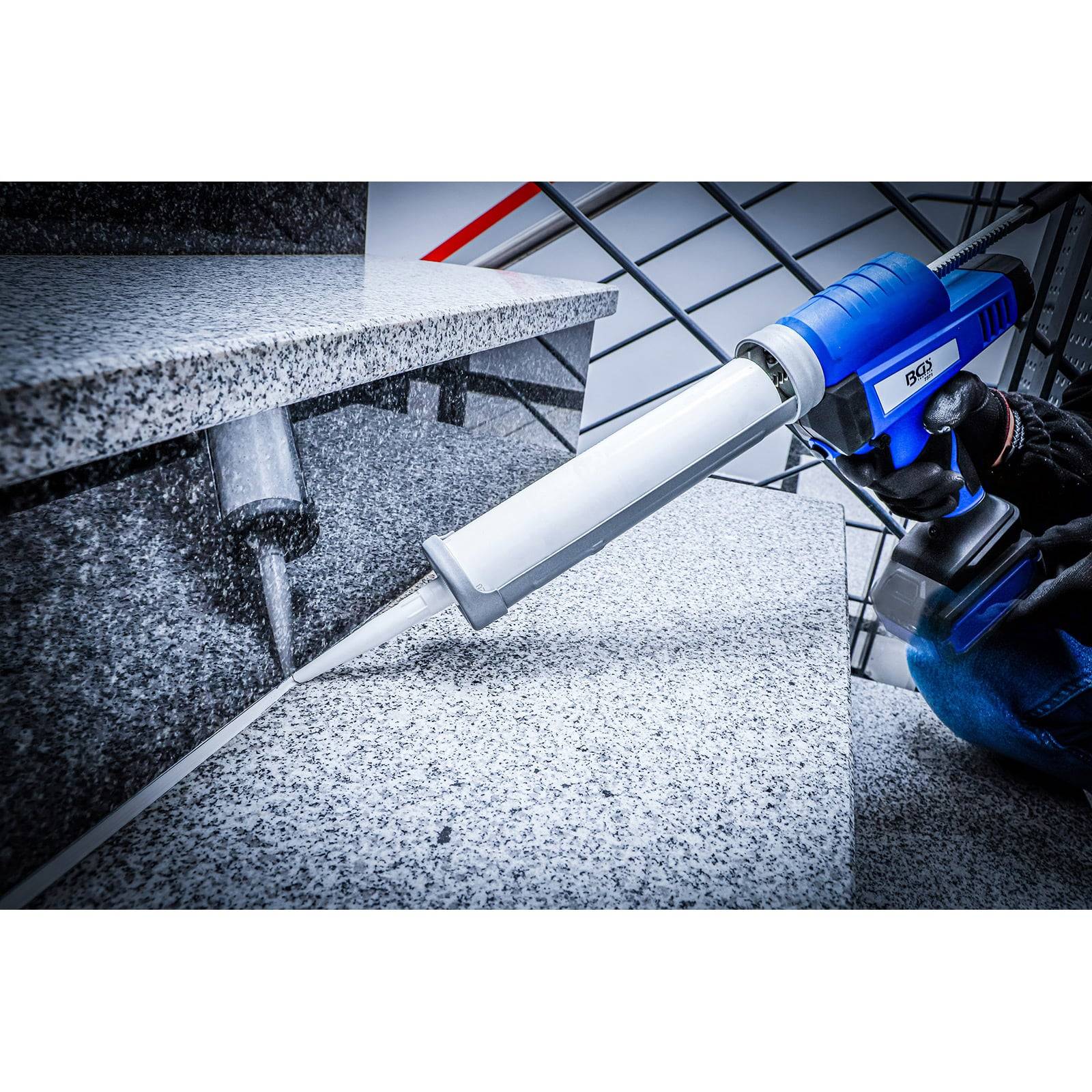 Eine Person hält eine Kartuschenpistole und dichtet eine Fuge zwischen grauen Granittreppenstufen und der Wand ab, um einen sauberen und sicheren Abschluss zu gewährleisten.