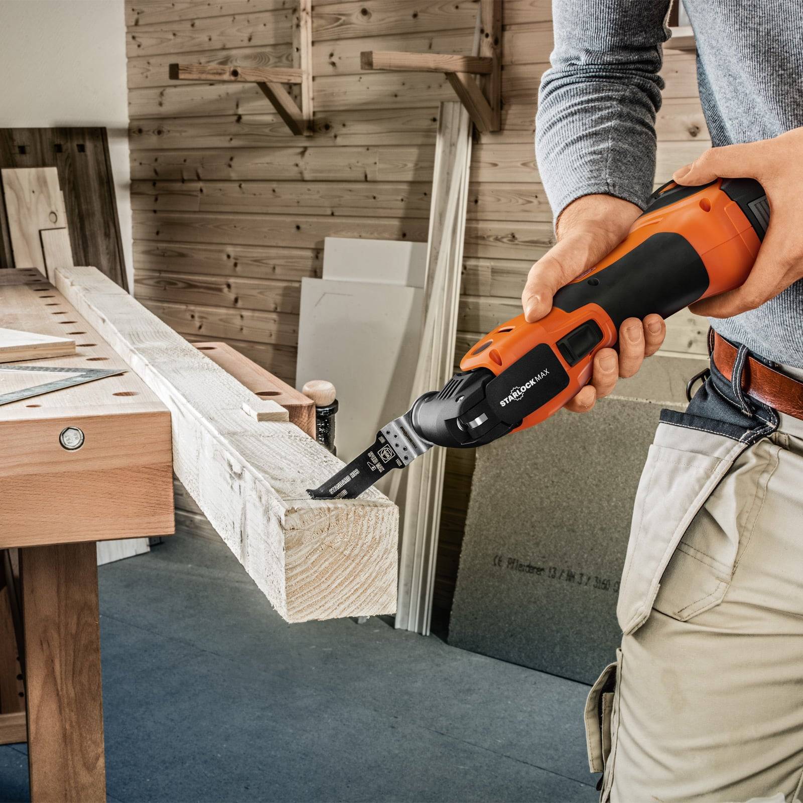 Eine Person, die in einer Werkstattumgebung eine kabellose Säge verwendet, um einen Holzbalken zu zersägen und dabei die Benutzerfreundlichkeit und Präzision des Werkzeugs demonstriert.