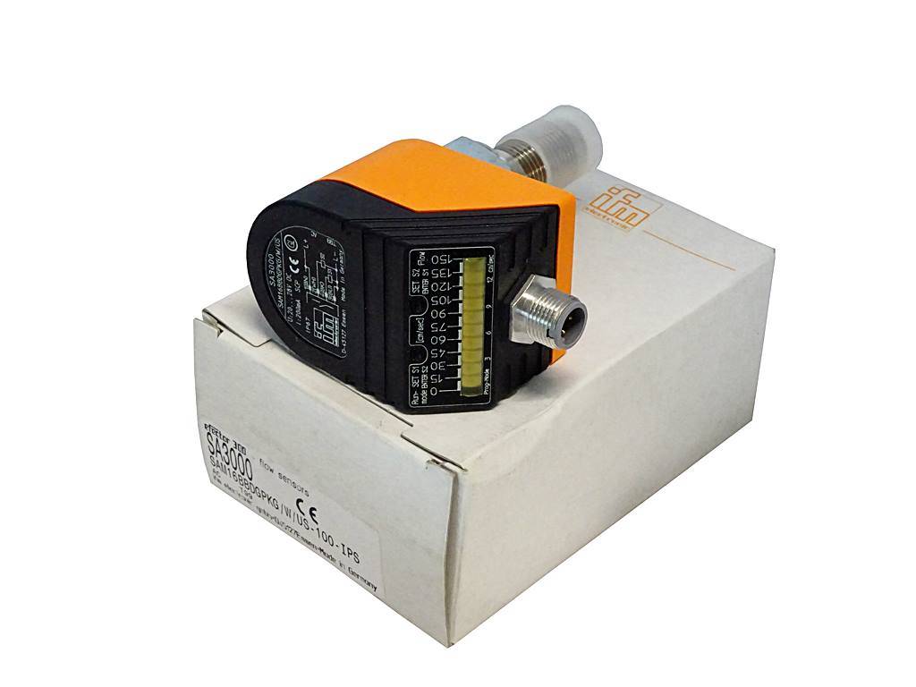 Industriesensor mit orange-schwarzem Gehäuse, auf einer weißen Schachtel liegend, freigestellt in produktähnlicher Darstellung vor einem schlichten Hintergrund.