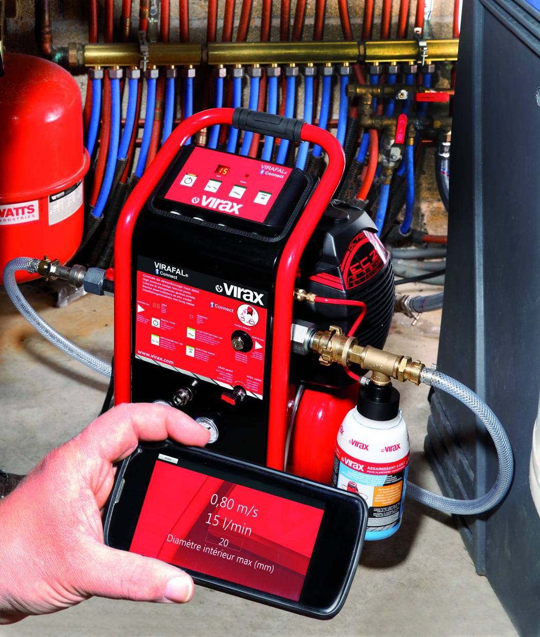 Eine Nahaufnahme eines Virax-Druckprüfgeräts mit roten Akzenten, das an ein Rohrsystem angeschlossen ist und Ableseangaben auf einem Bildschirm zeigt.