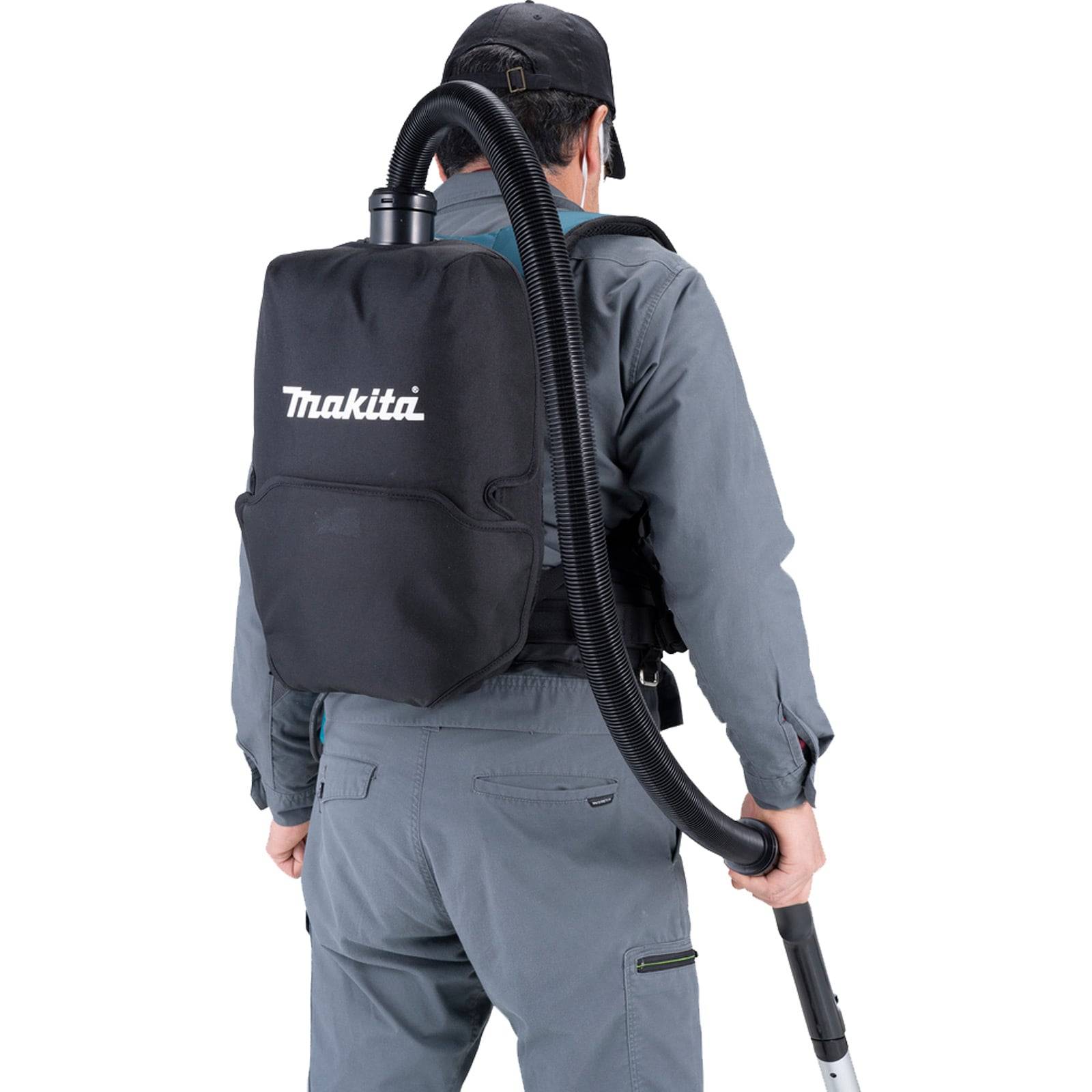 Eine Person, die einen Makita-Rückenvakuumreiniger trägt und mit Arbeitskleidung bekleidet, von hinten zu sehen.