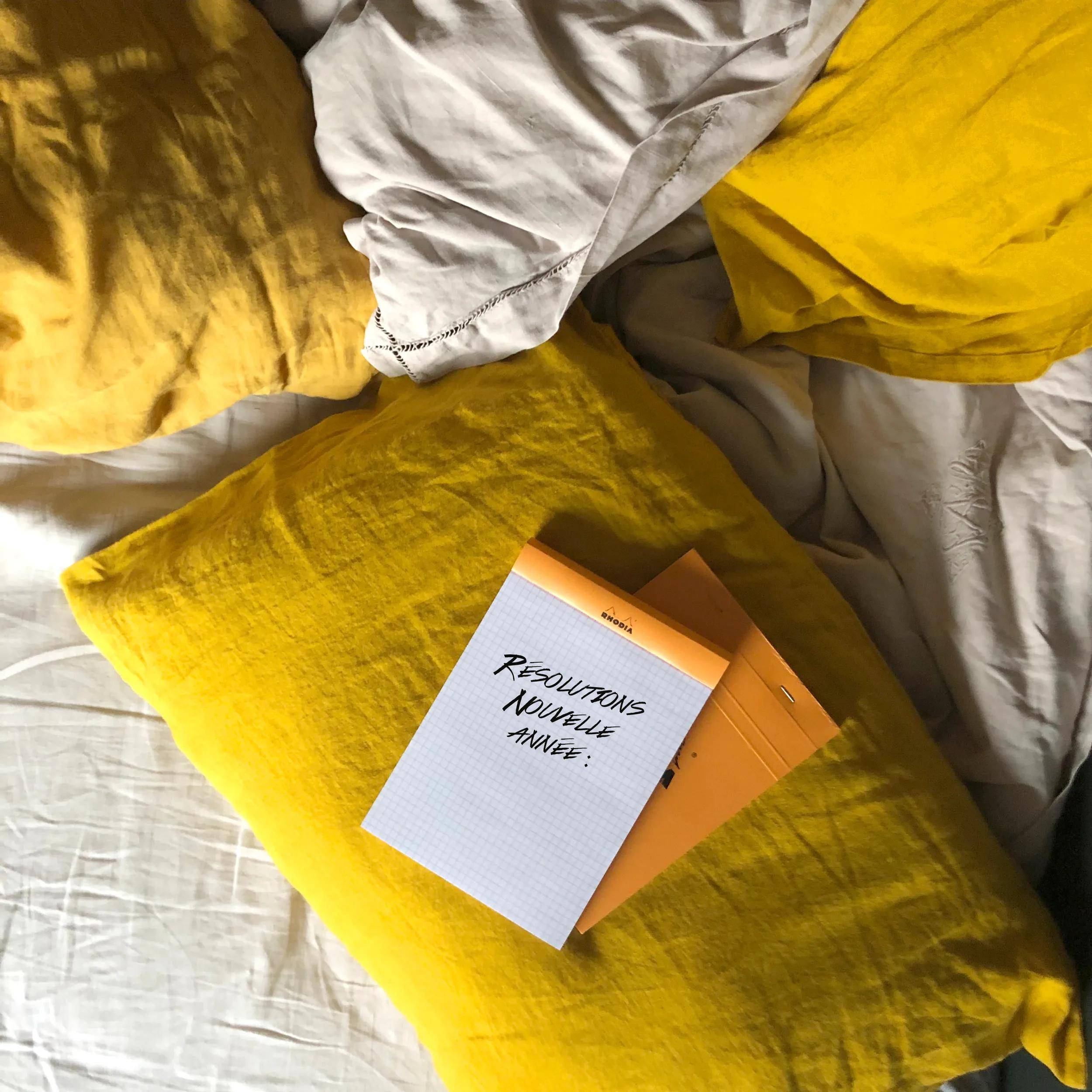 Ein Stapel aus zwei gelben Notizblöcken auf gelben Kissen, wobei einer mit 