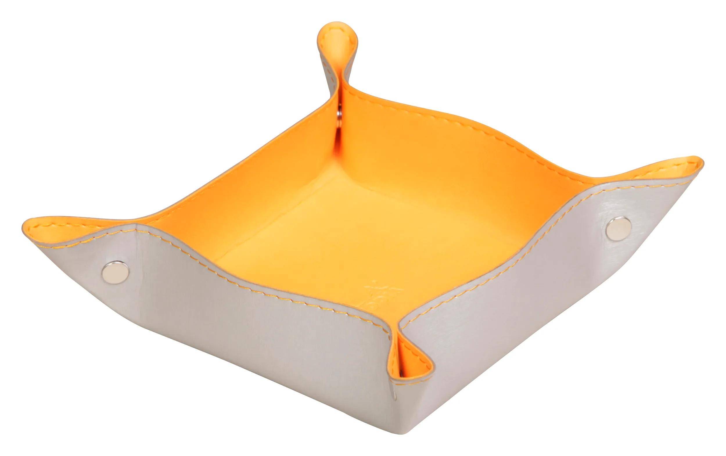 Ein weißes Ledertablett mit erhöhten Ecken und orangefarbenem Innenraum, das zur Organisierstion kleiner Gegenstände verwendet wird.