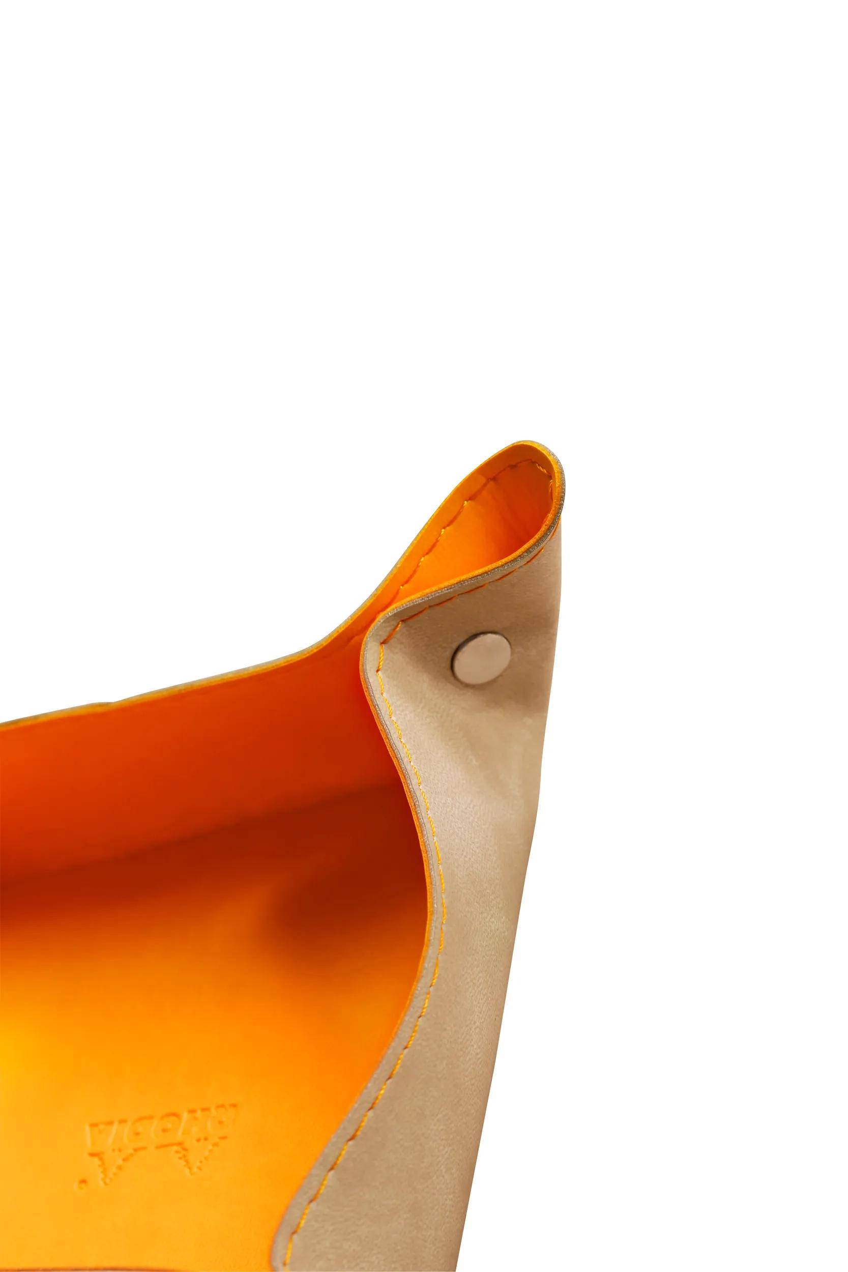 „Nahaufnahme einer offenen beigefarbenen Ledertasche mit orangefarbenem Innenfutter und Druckknopfverschluss.