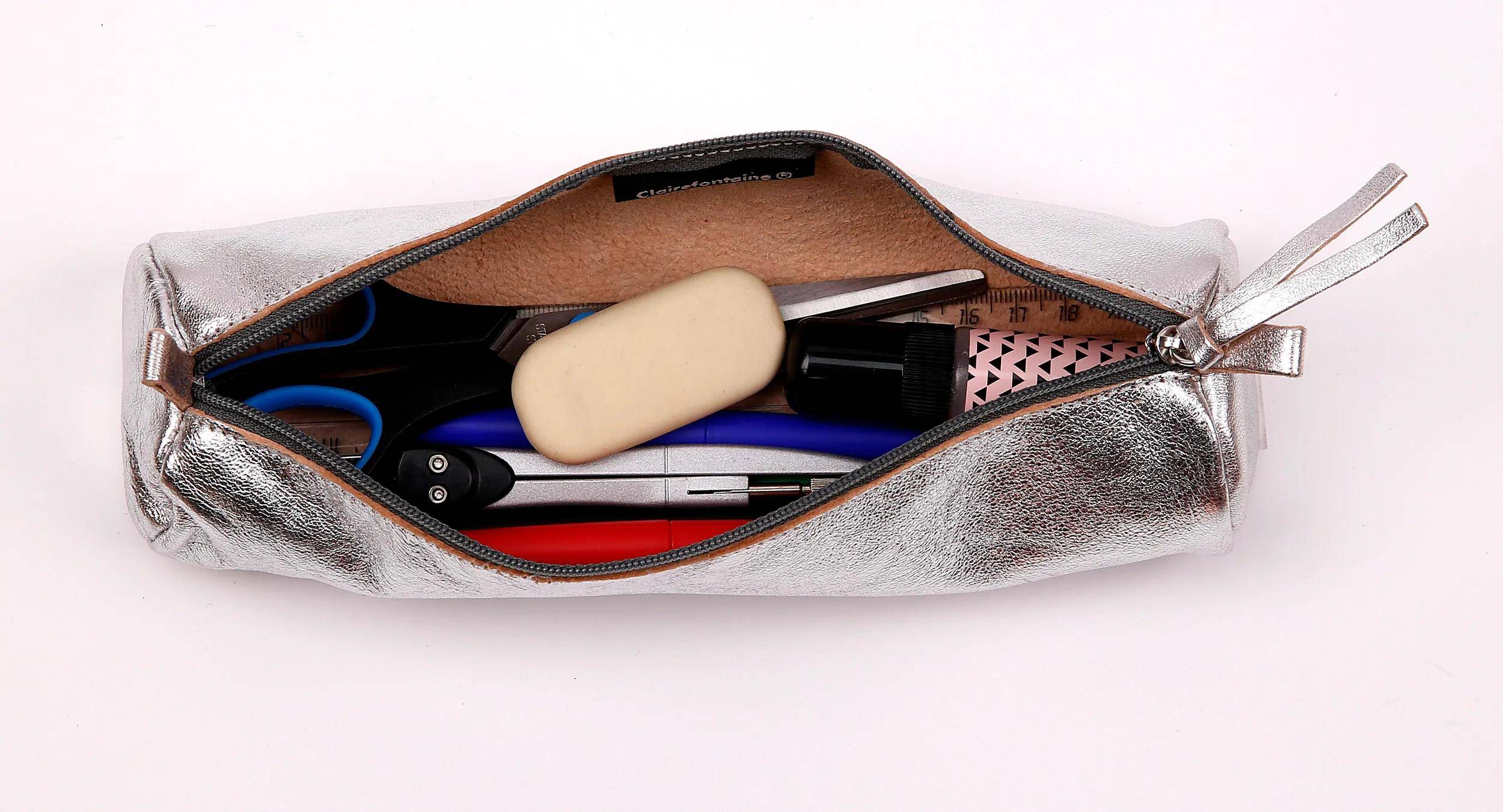 Offene Federtasche mit Radiergummi, Schere, Stift, Lineal und Markern.