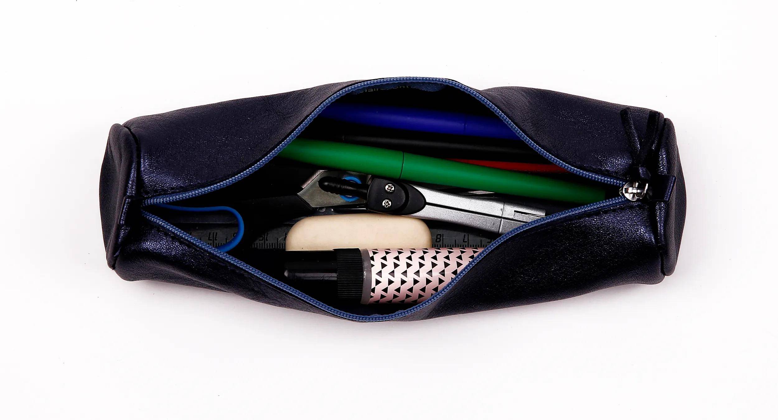 Offene schwarze Kulturtasche mit blauem Rand, die eine Zahnbürste, eine Haarbürste und andere Reisepflege-Artikel im Inneren zeigt.