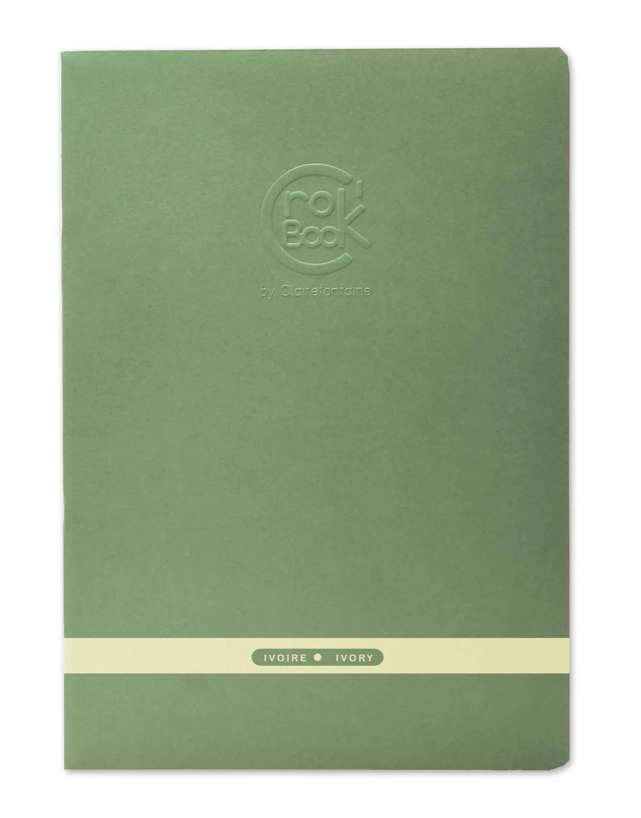 Grünes Notizbuch mit geprägtem Kreislogo und einem cremefarbenen Band mit der Beschriftung „IVOIRE • IVORY