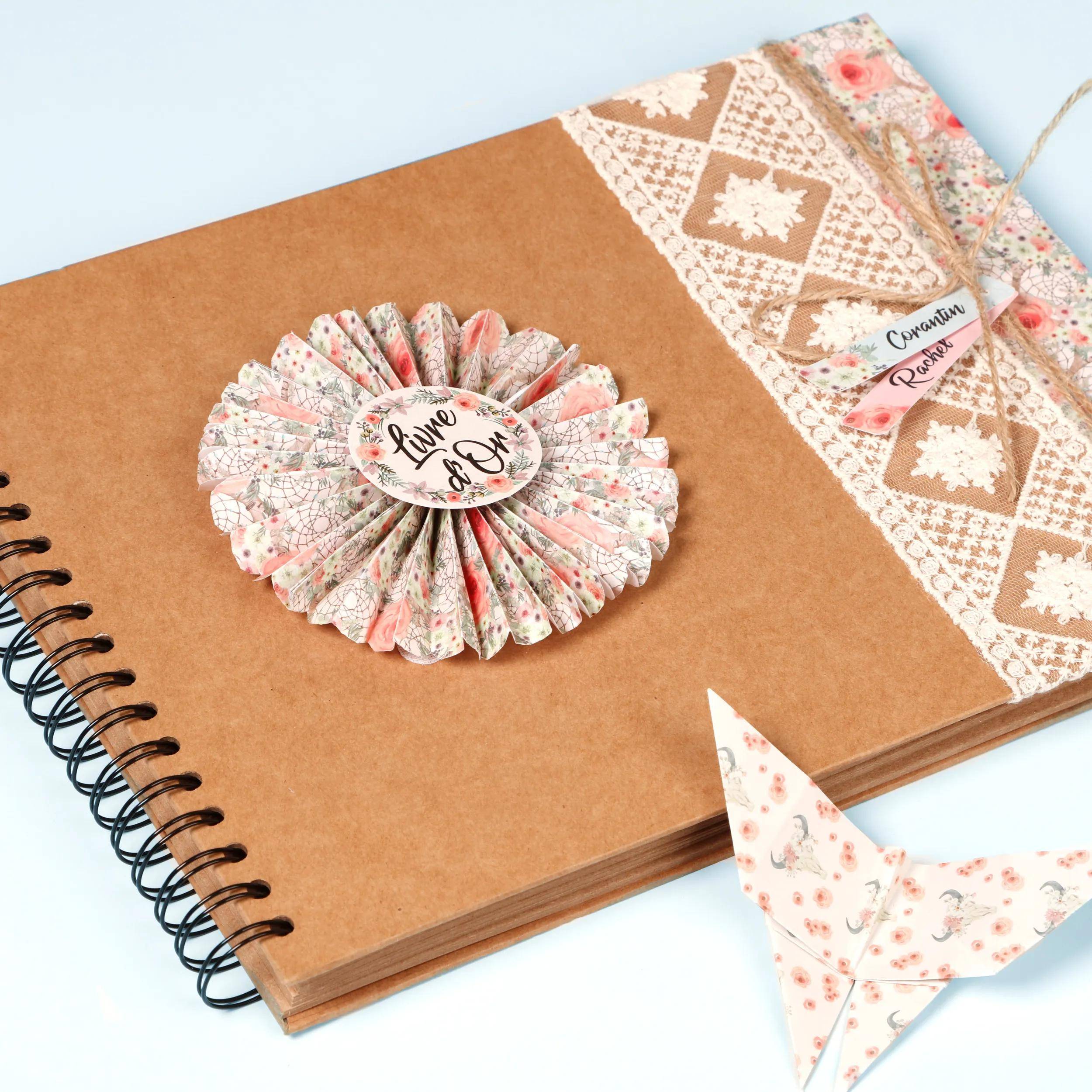 Dekoriertes braunes spiral-gebundenes Scrapbook mit Blumenpapier-Rosette und Spitzenmuster-Eckverzierung, plus gefaltete Papier-Origami-Form.