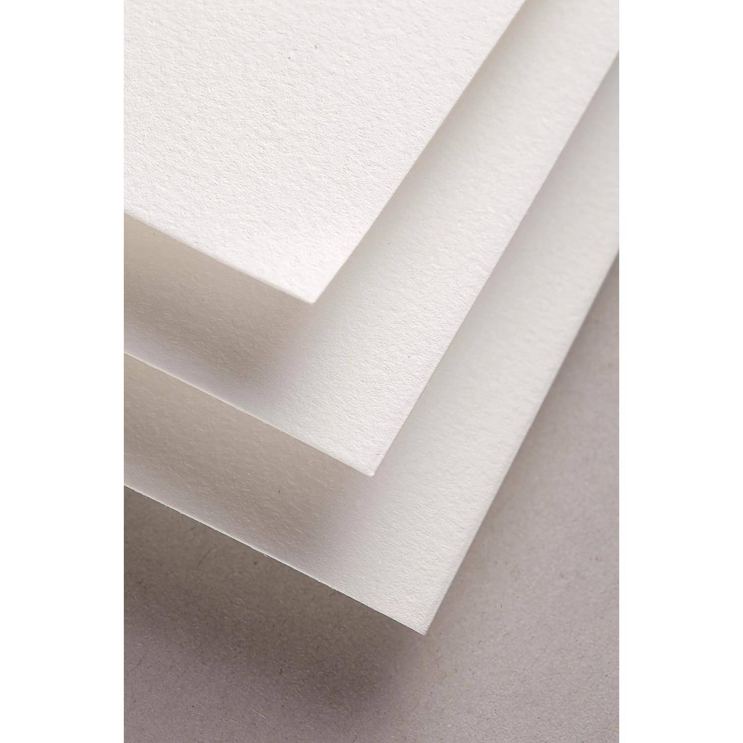 Gestapelte Blätter aus strukturiertem weißem Papier, die sich auf einer neutralen grauen Oberfläche überlappen, in Nahaufnahme gezeigt.