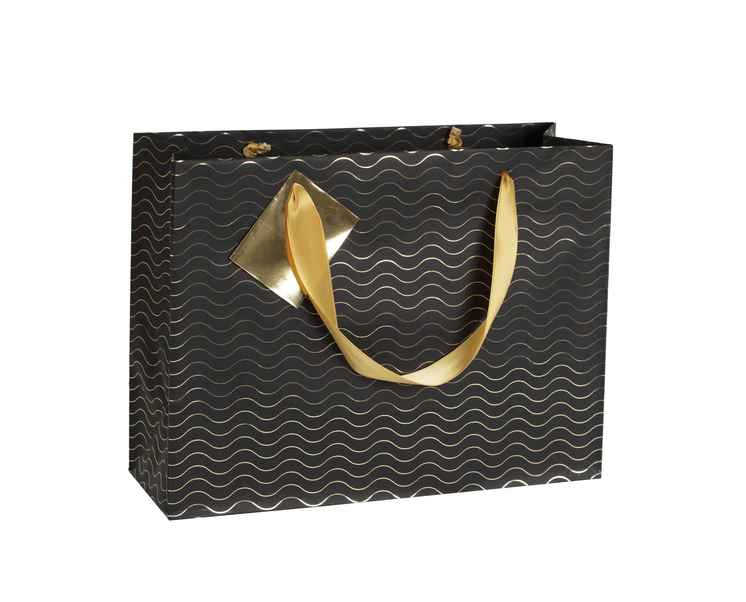 Schwarze gemusterte Geschenktasche mit goldfarbenen Bandgriffen auf weißem Hintergrund