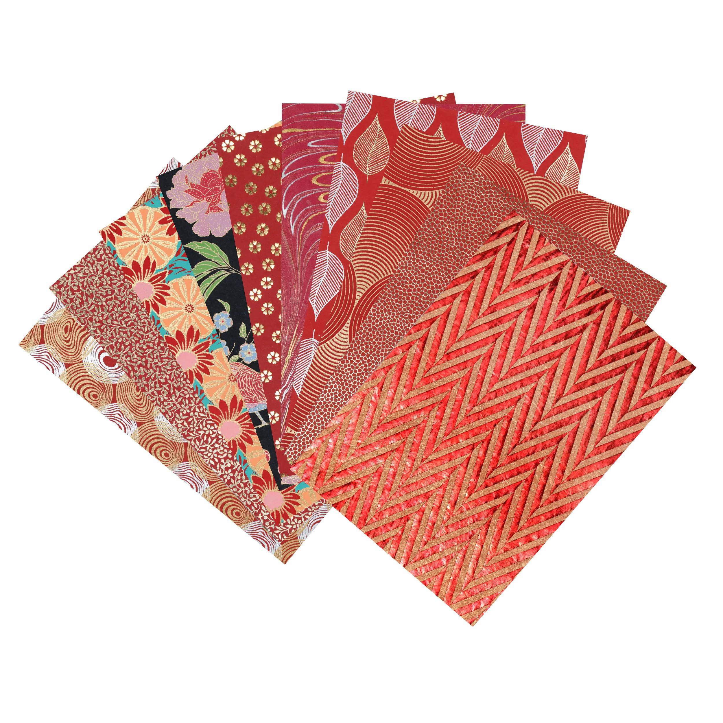 Sortierte gefaltete dekorative Papiertücher mit roten und mehrfarbigen Blumen- und geometrischen Mustern, fächerartig auf weißem Hintergrund ausgebreitet.