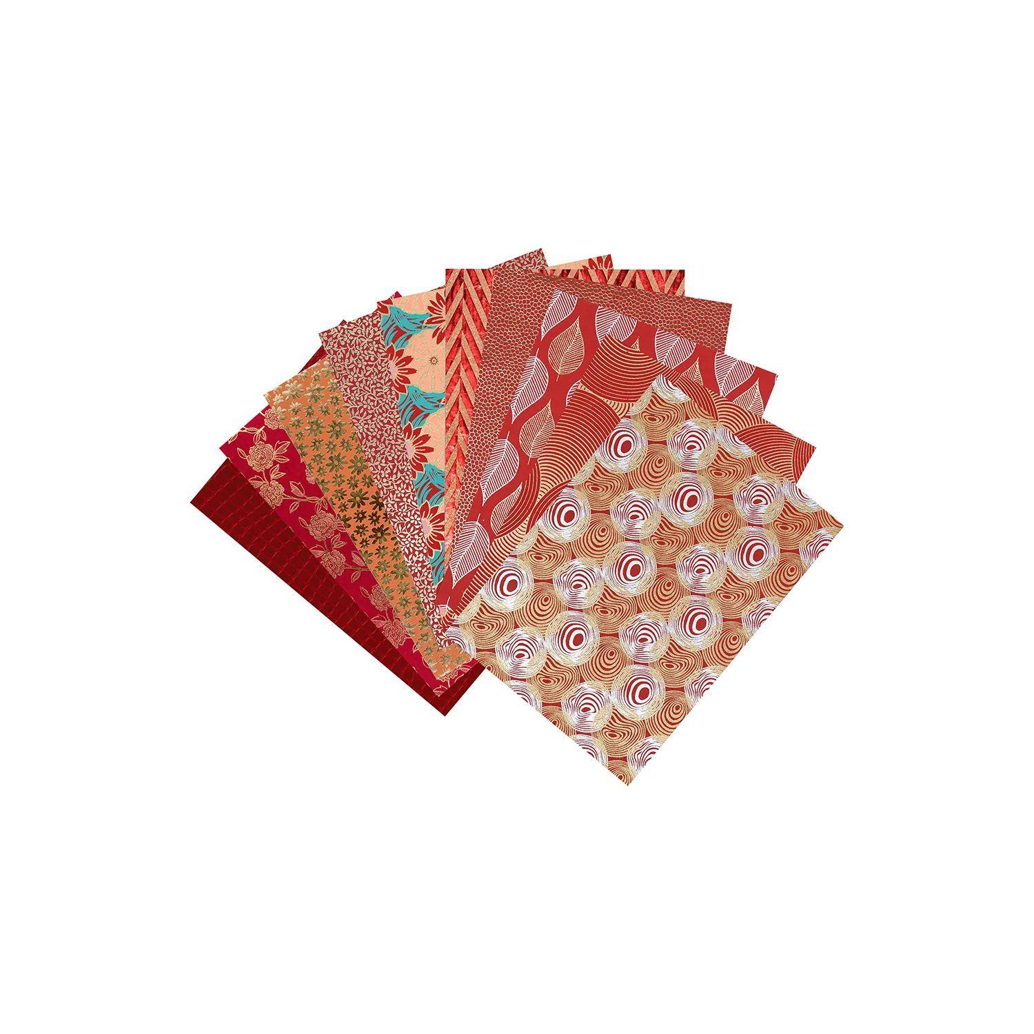 Stapel dekorativer gemusterter Papiere in Rot, Rosa und Beige mit floralen und geometrischen Designs auf weißem Hintergrund.