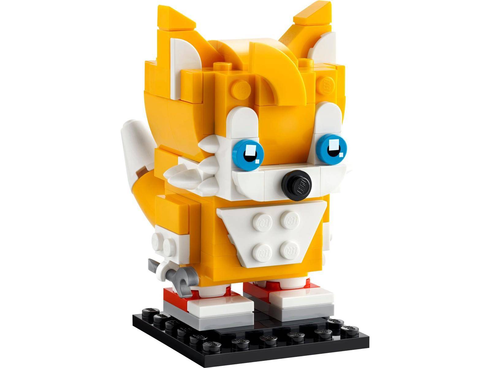 Gelbe und weiße LEGO-ähnliche Fuchsfigur mit blauen Augen, stehend auf einer schwarzen Basis.