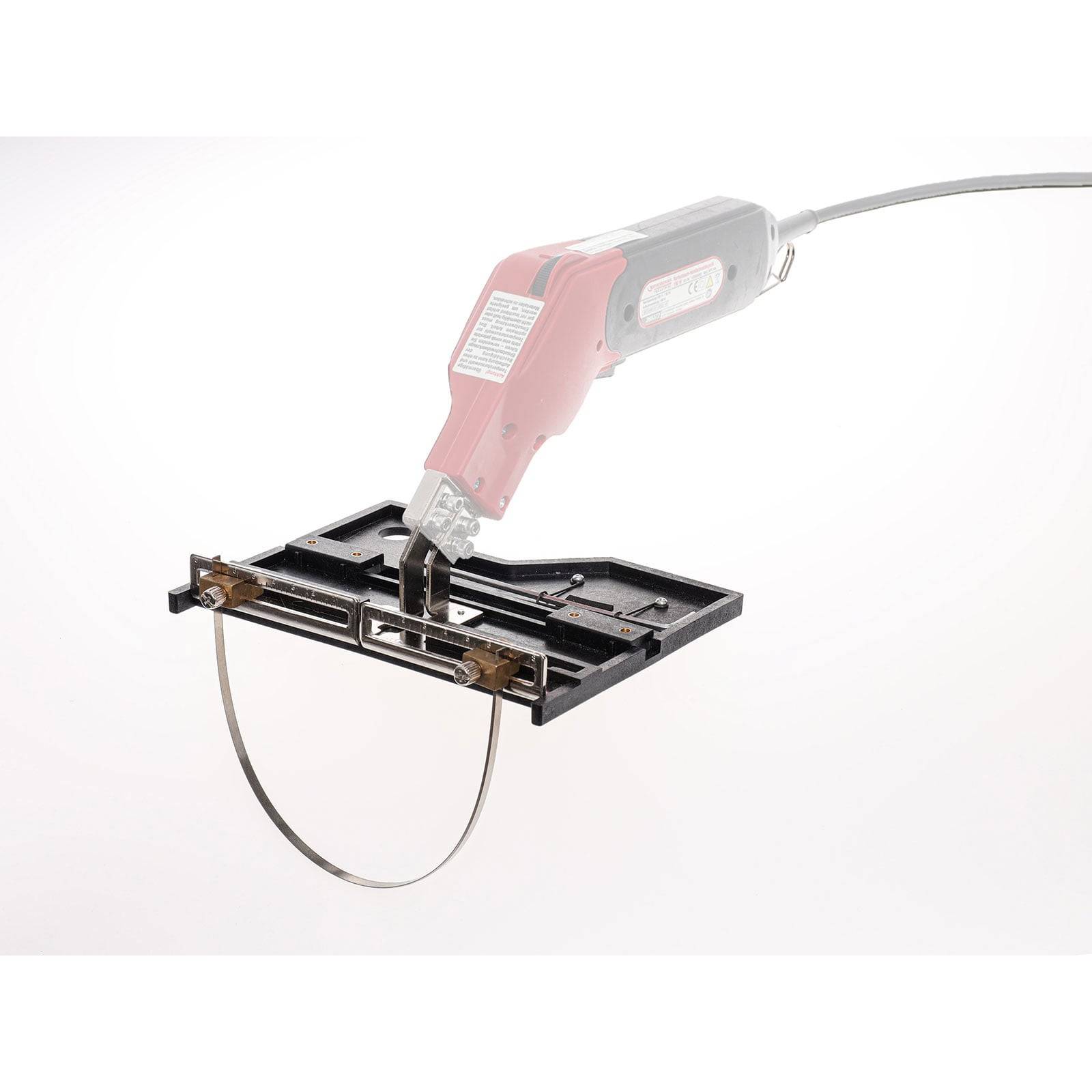 Ein rot-schwarzes elektrisches Handwerkzeug mit einer dünnen Klinge in einem Metallrahmen, wahrscheinlich zum Schneiden oder für präzise Formarbeiten verwendet.