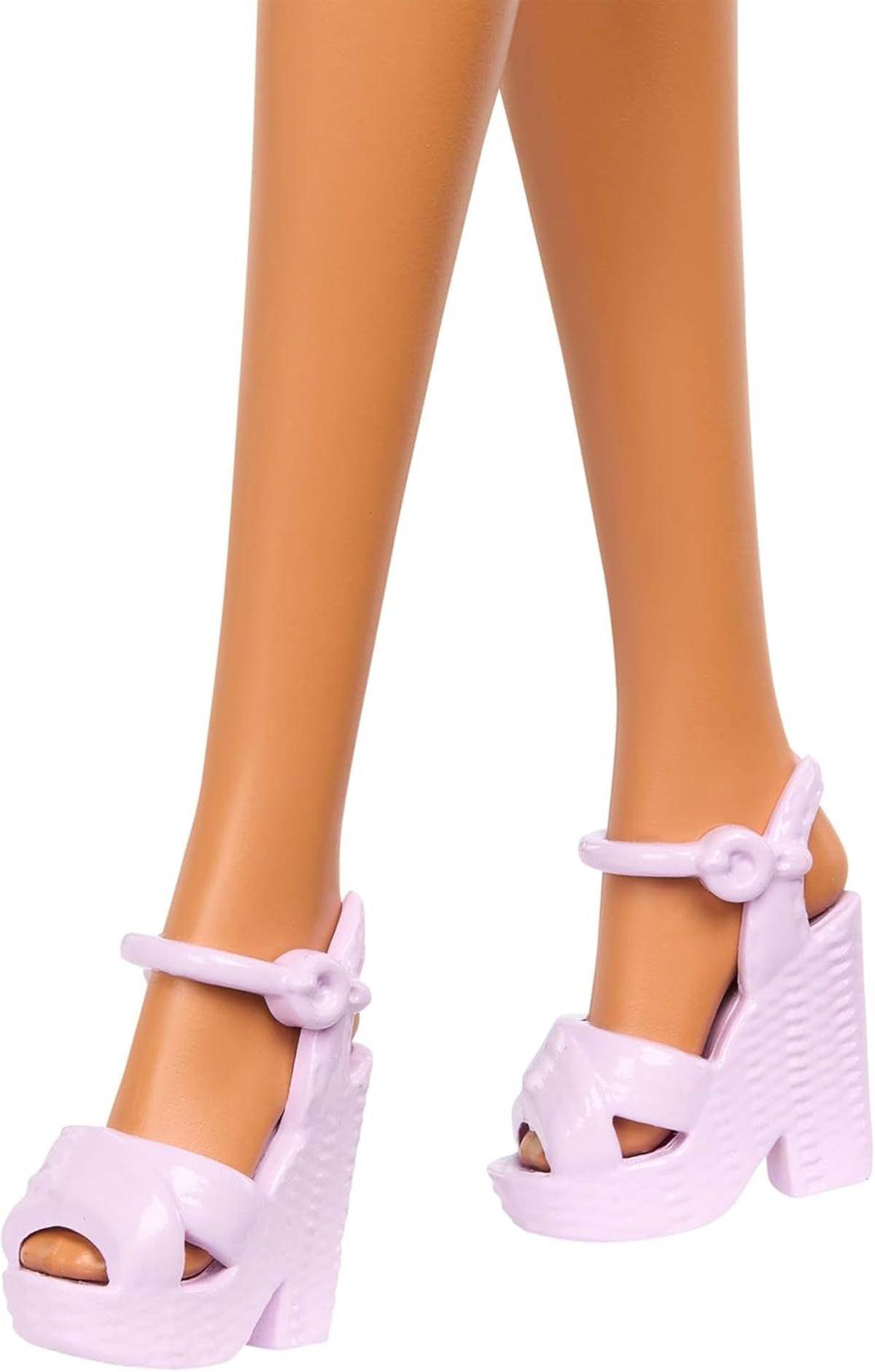 Nahaufnahme der Unterschenkel einer Puppe, die hellrosa High-Heel-Plateausandalen mit Knöchelriemen und offenen Zehen trägt.