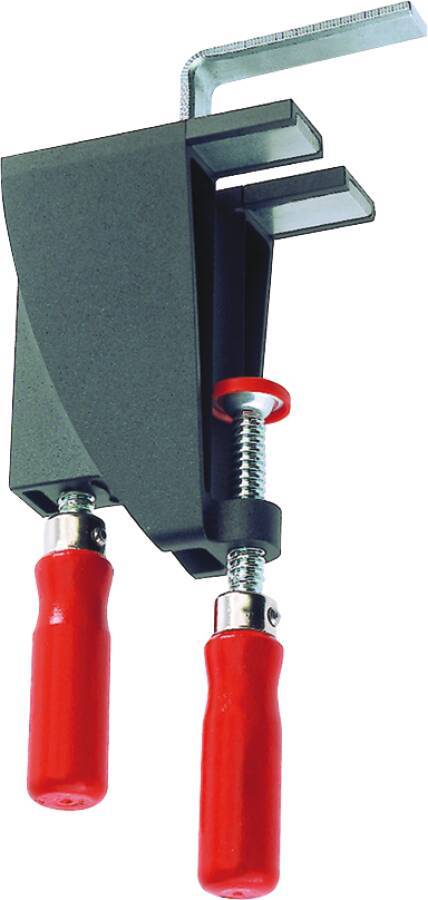 Eine Nahaufnahme eines Metallspannwerkzeugs mit zwei roten Griffen und einem Schraubenmechanismus, der ein dunkles rechteckiges Objekt gegen eine Oberfläche spannt.