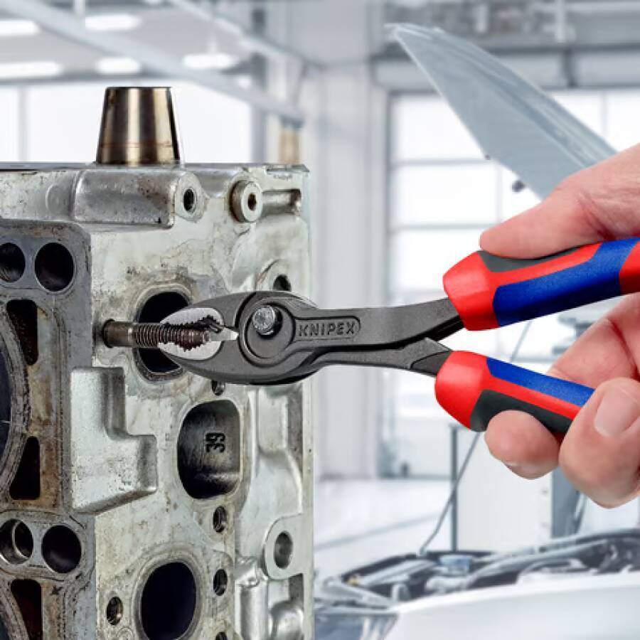 Hand verwendet KNIPEX-Zange zum Greifen und Entfernen eines abgebrochenen Bolzens aus einem Metall-Motor oder Maschinenteil in einer Werkstatt.
