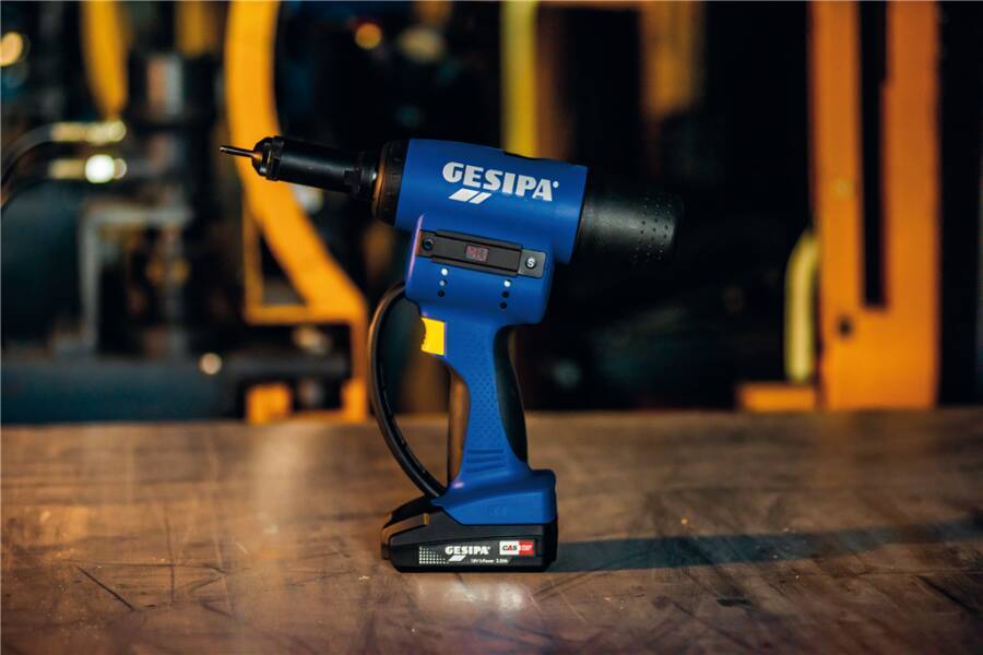 Blaue kabellose GESIPA-Nietpistole, die auf einer Holzwerkbank in einer Werkstatt steht