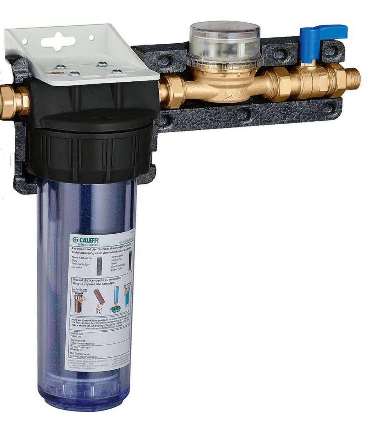 Wandmontierter Wasserfilter mit durchsichtigem Filtergehäuse, Messingrohrleitung und blauem Absperrventil auf einer Halterung.
