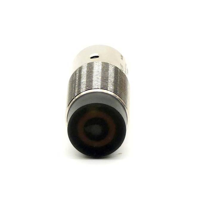 Nahaufnahme eines kleinen zylindrischen Metallsensors oder einer Kameraobjektivlinse mit einer schwarzen kreisförmigen Vorderseite, gezeigt auf weißem Hintergrund.