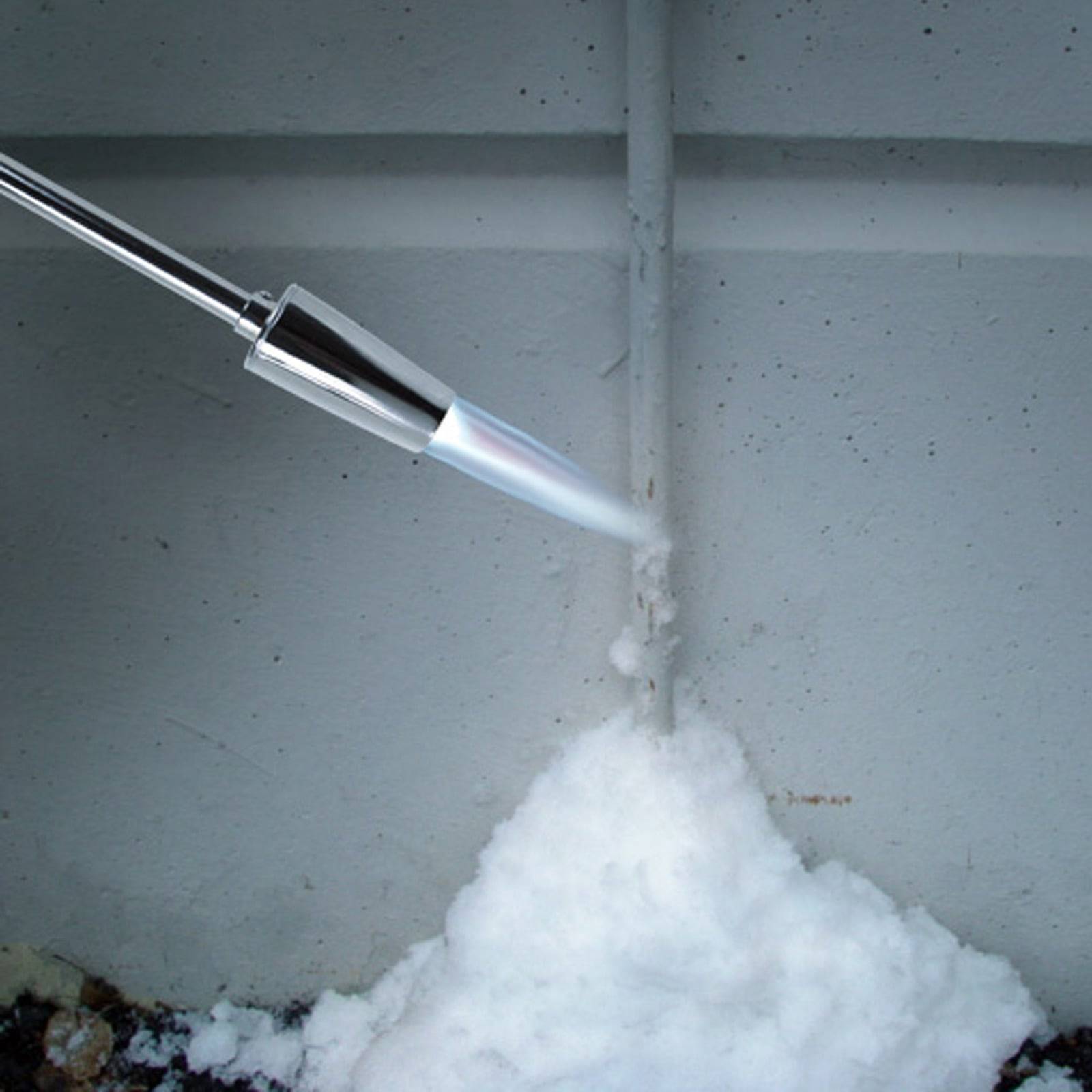 Ein Gasbrenner wird verwendet, um Eis auf einer Betonoberfläche zu schmelzen, wobei ein Flammenstrahl direkt auf das Eis gerichtet ist.